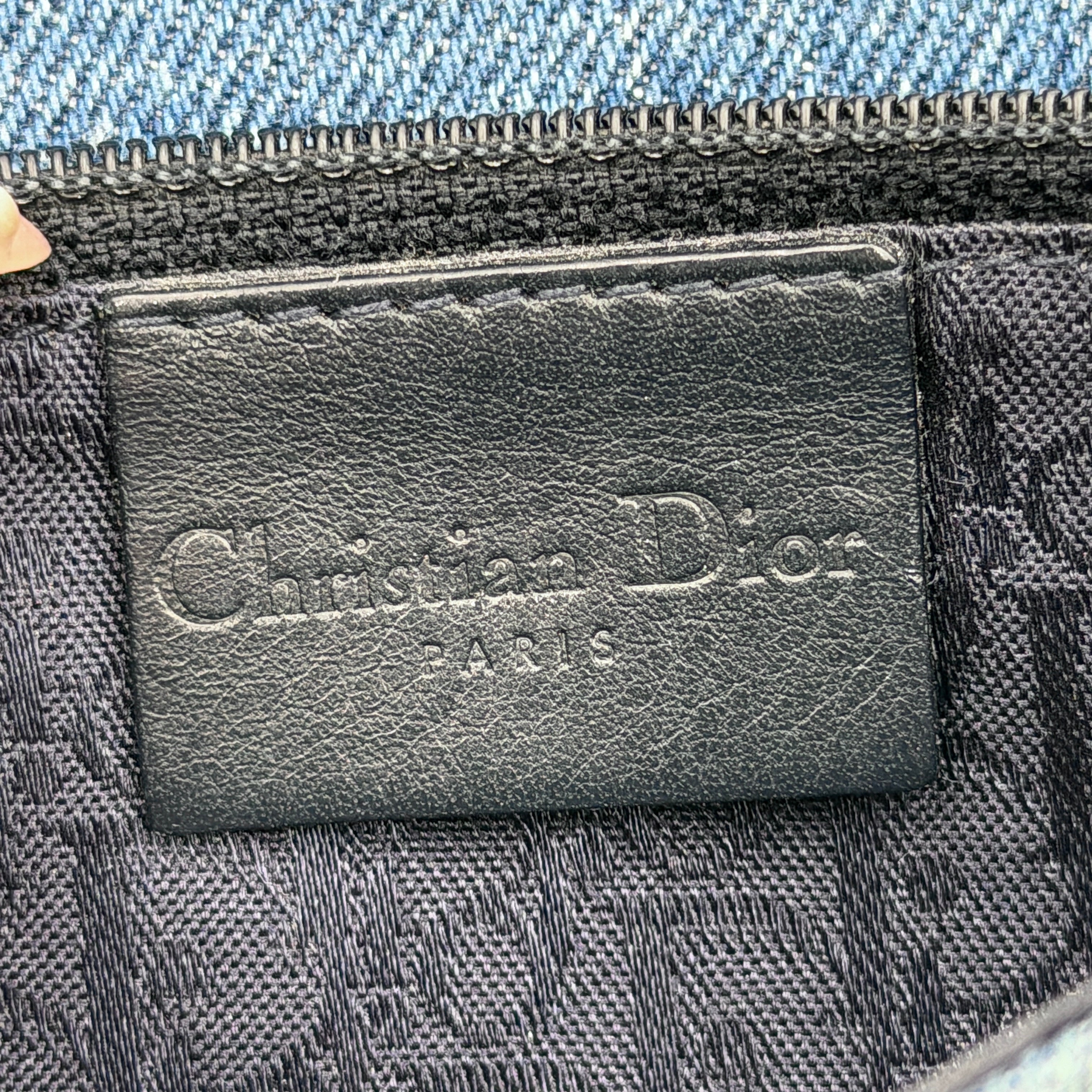 Dior Saddle Denim Wallet in blue denim with signature curved silhouette and silver-tone 'D' charm on the front flap.