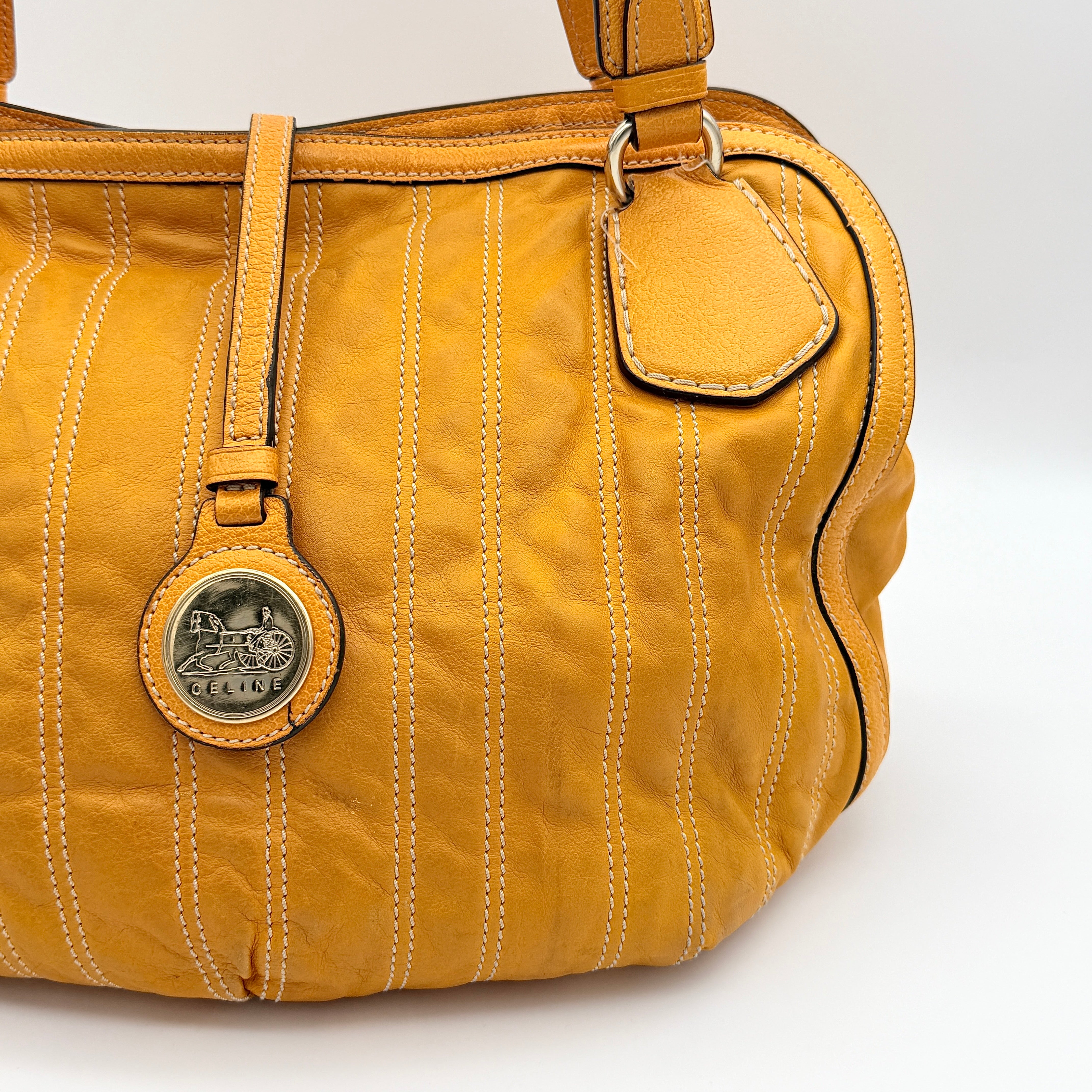 Celine Stripe Hobo Shoulder Bag in yellow leather with vertical stitching and signature gold-tone medallion, shown with dual handles.