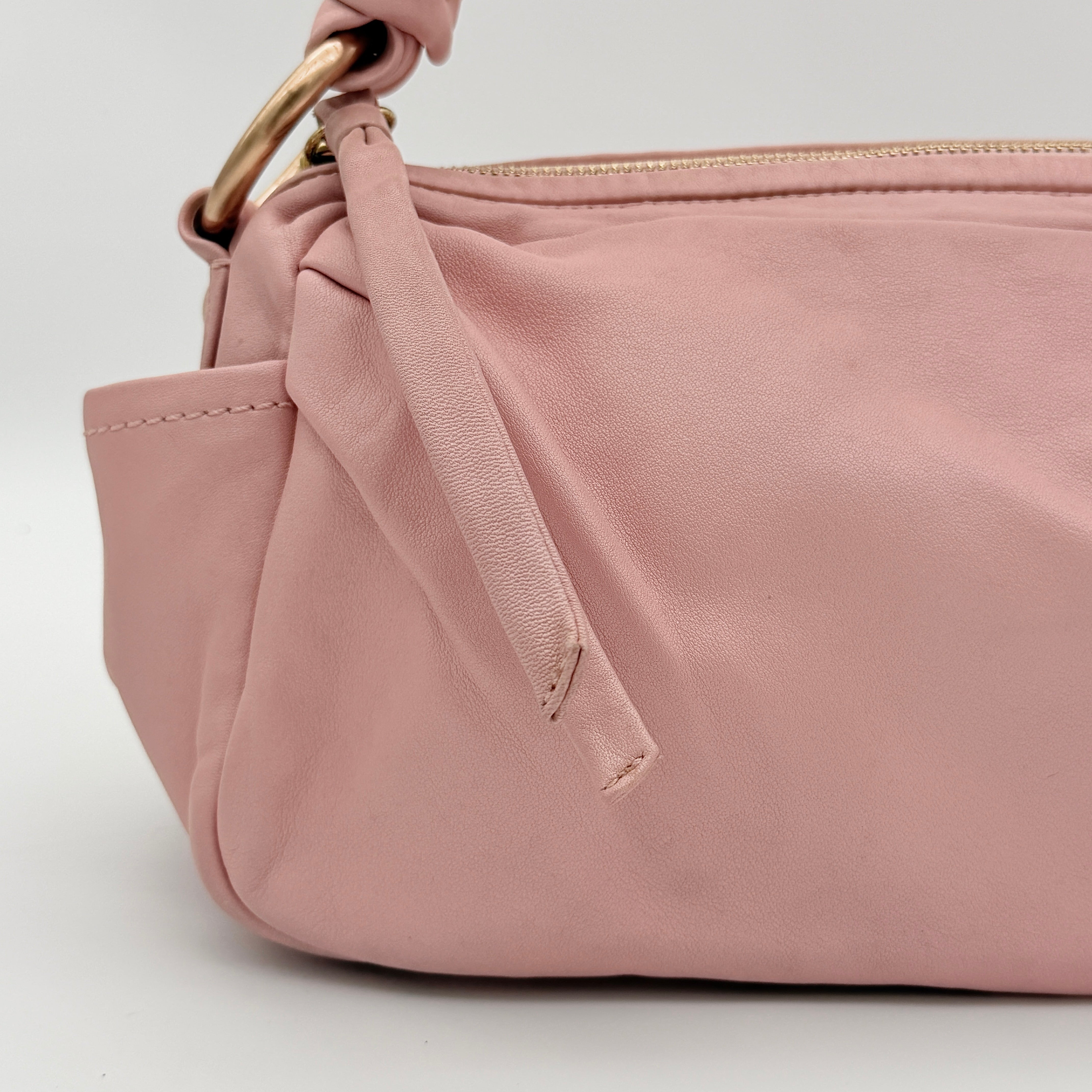 Coach pink leather hobo shoulder bag with knotted handle, gold-tone hardware, and side pockets.