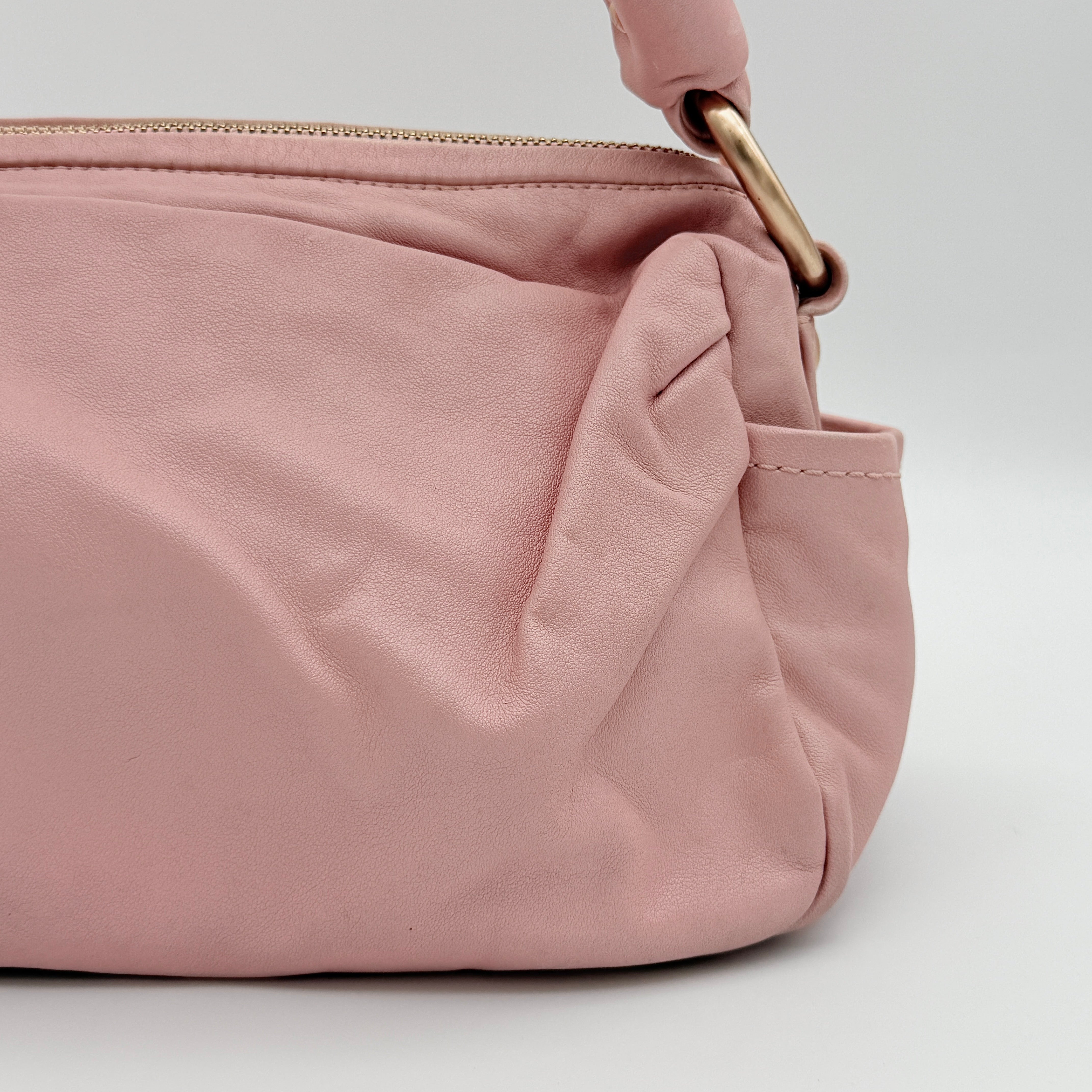 Coach pink leather hobo shoulder bag with knotted handle, gold-tone hardware, and side pockets.