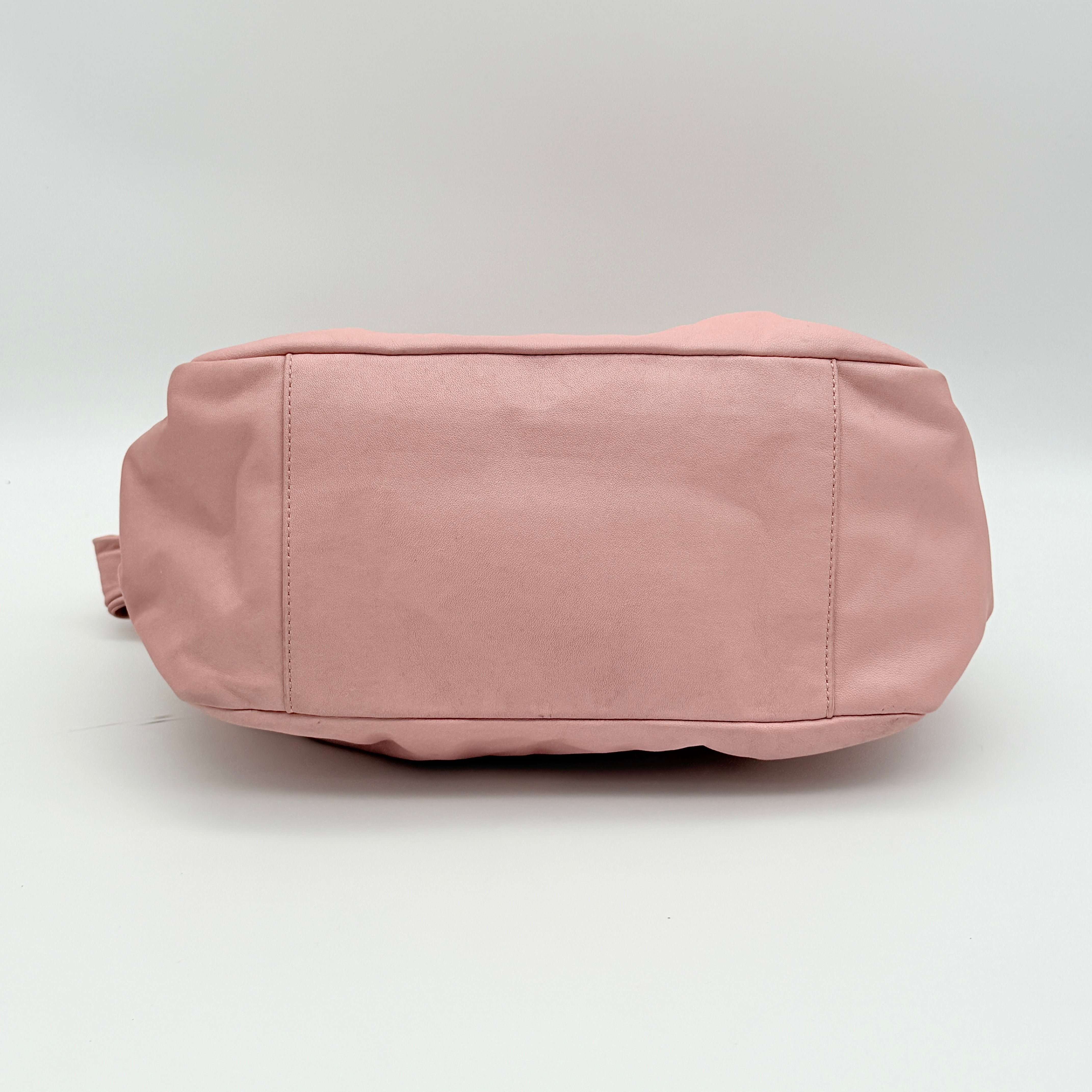 Coach pink leather hobo shoulder bag with knotted handle, gold-tone hardware, and side pockets.