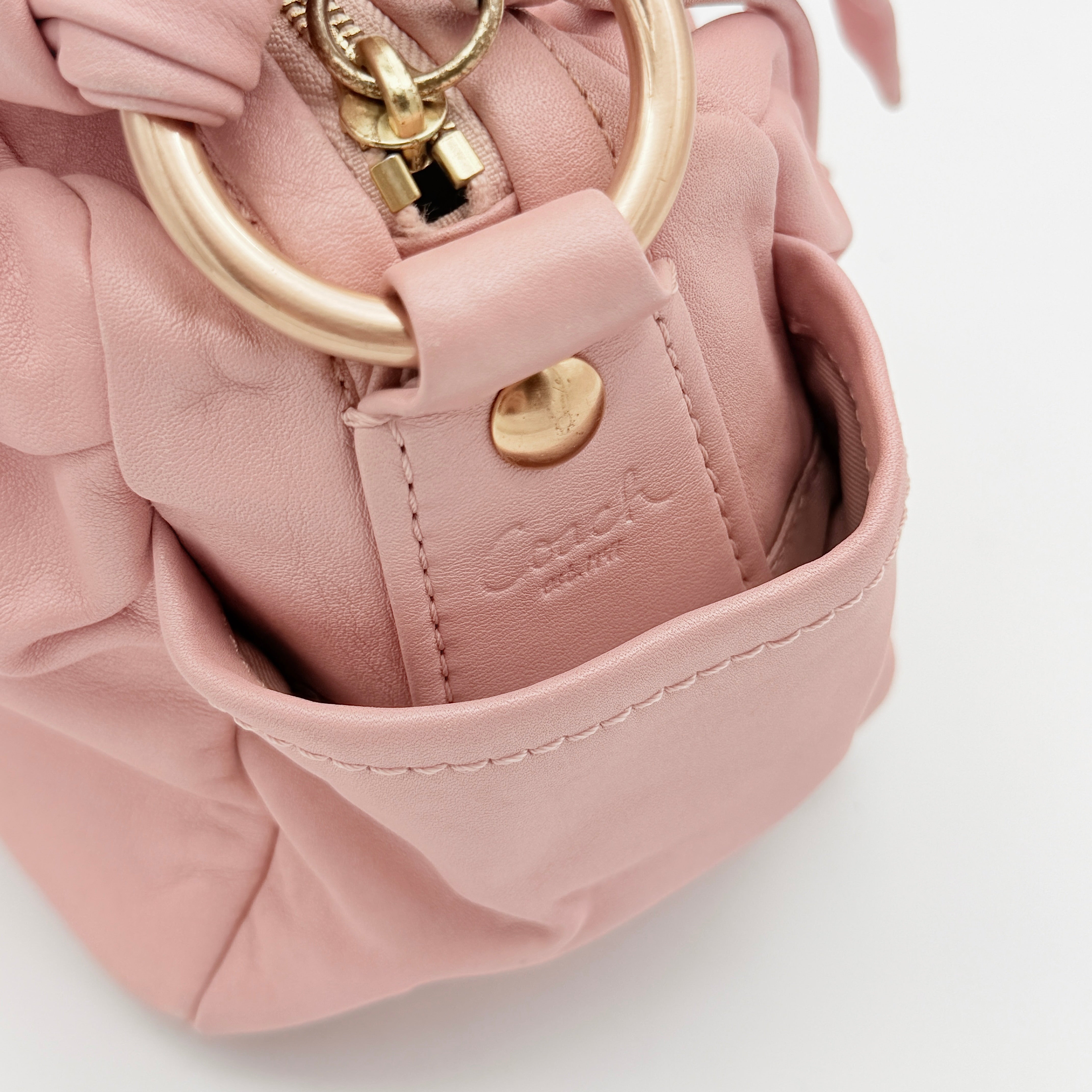 Coach pink leather hobo shoulder bag with knotted handle, gold-tone hardware, and side pockets.