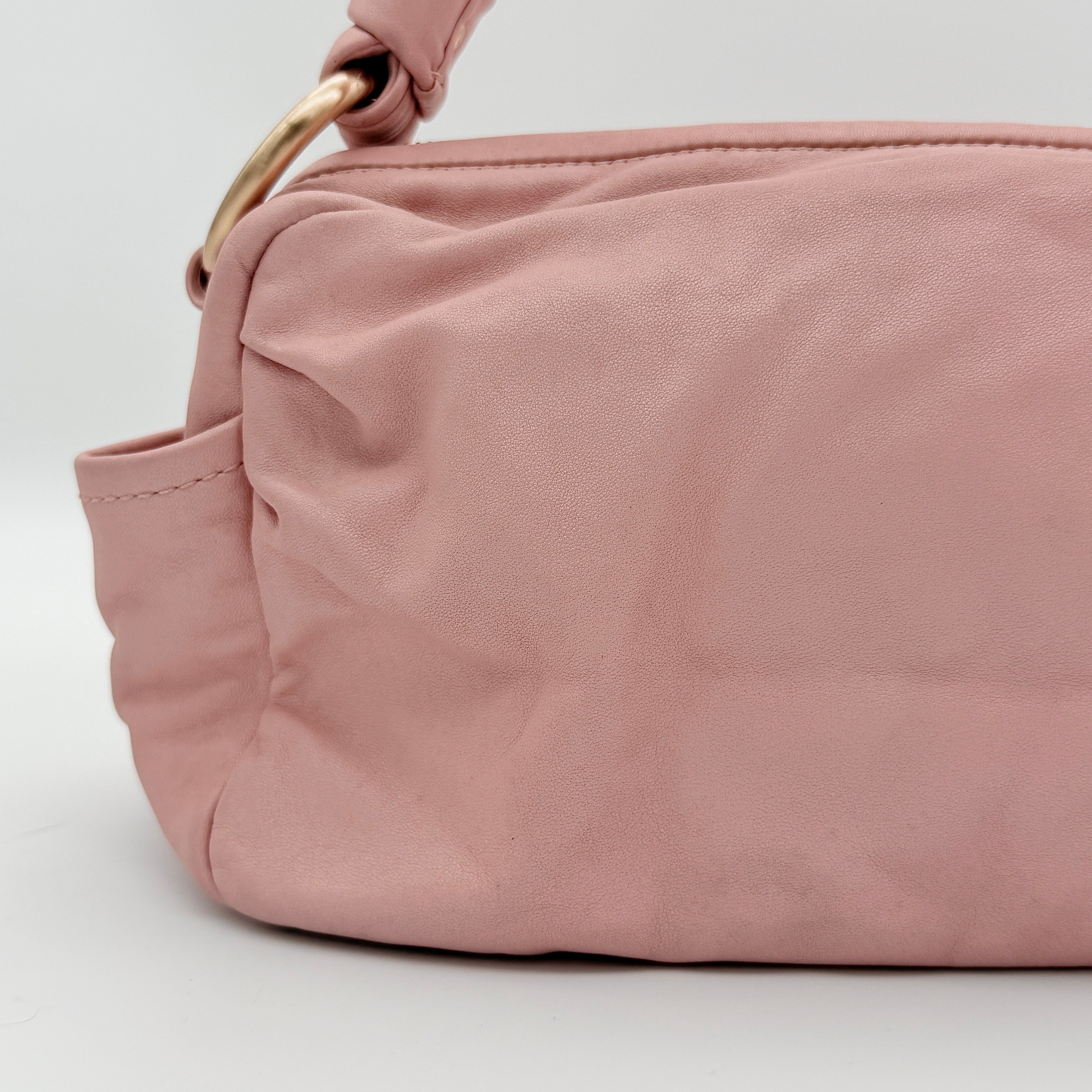 Coach pink leather hobo shoulder bag with knotted handle, gold-tone hardware, and side pockets.