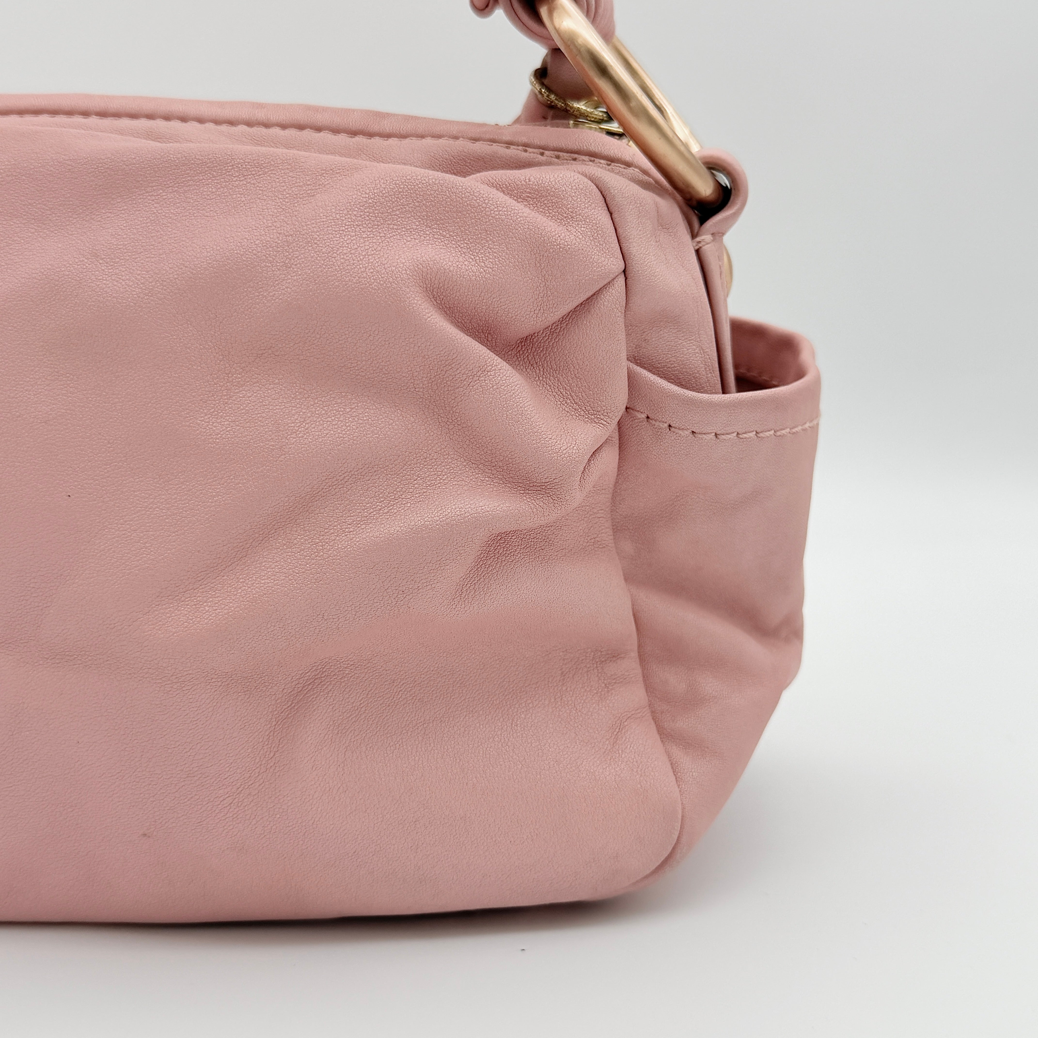 Coach pink leather hobo shoulder bag with knotted handle, gold-tone hardware, and side pockets.