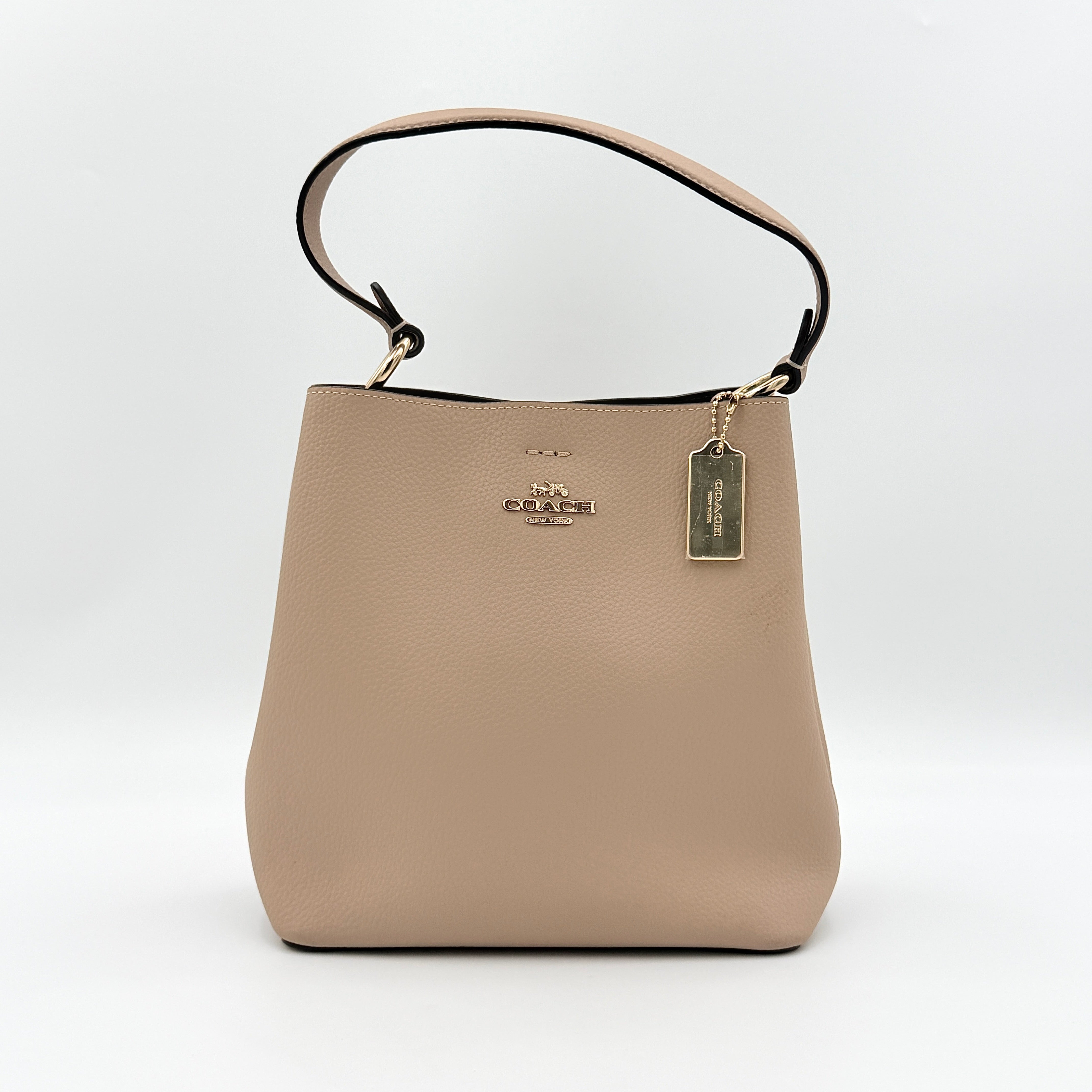 Coach Town Bucket Bag in taupe pebbled leather with gold-tone hardware and Coach hangtag, shown against a white background.