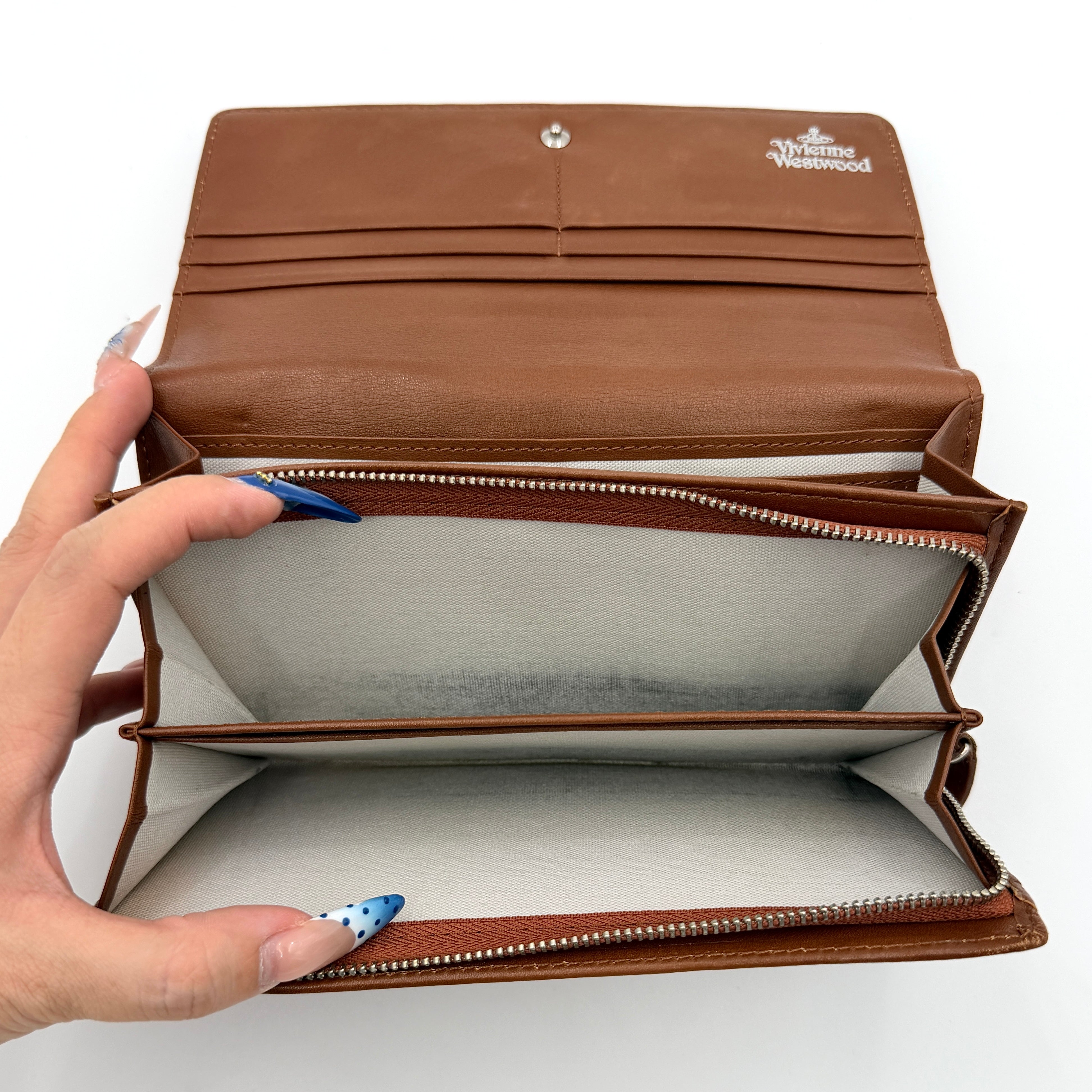 Vivienne Westwood long wallet in chestnut brown leather with white contrast stitching and silver orb embellishment.