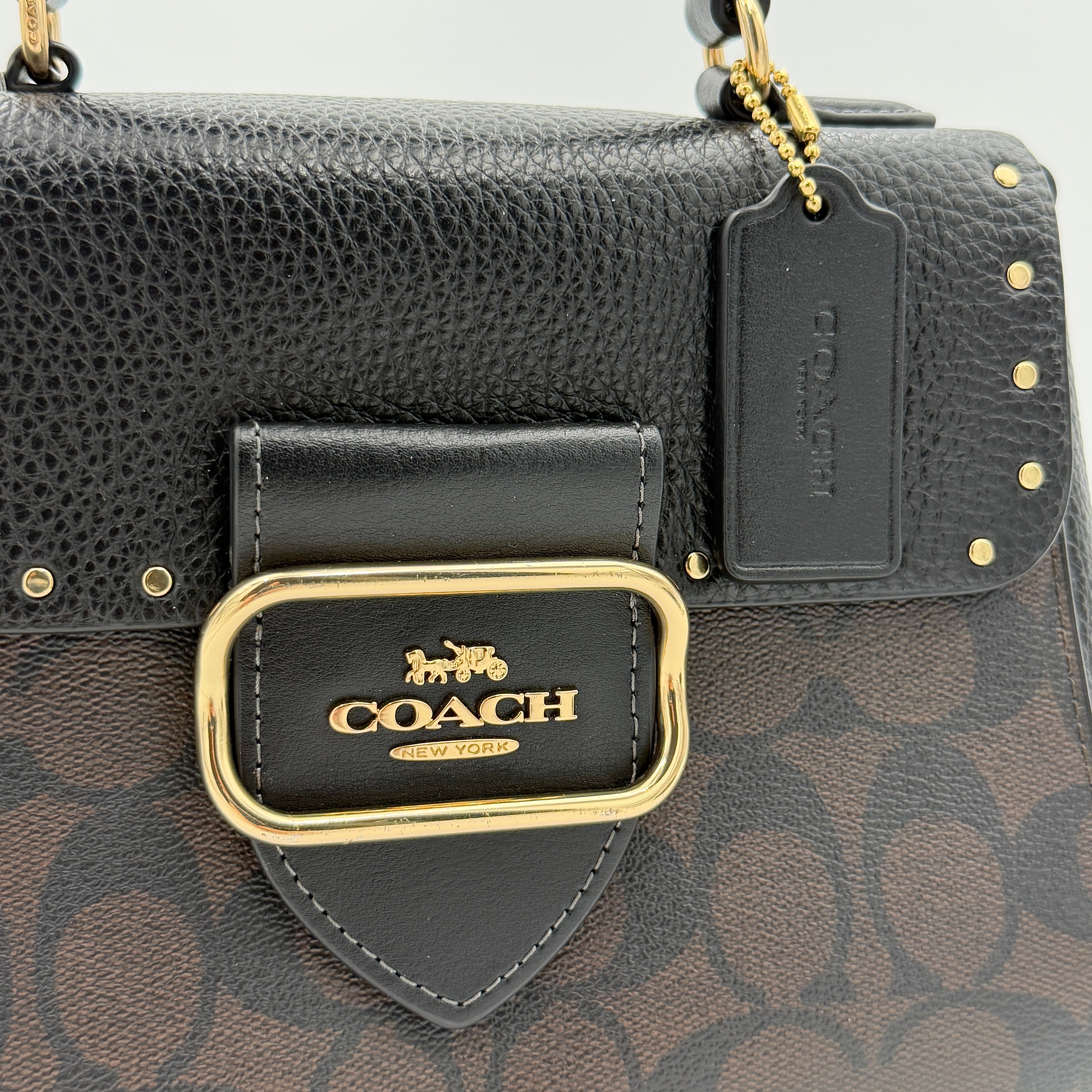 Coach Morgan Top Handle Bag in brown and black signature canvas with pebbled leather, gold hardware and detachable strap displayed alongside a Coach dustbag.