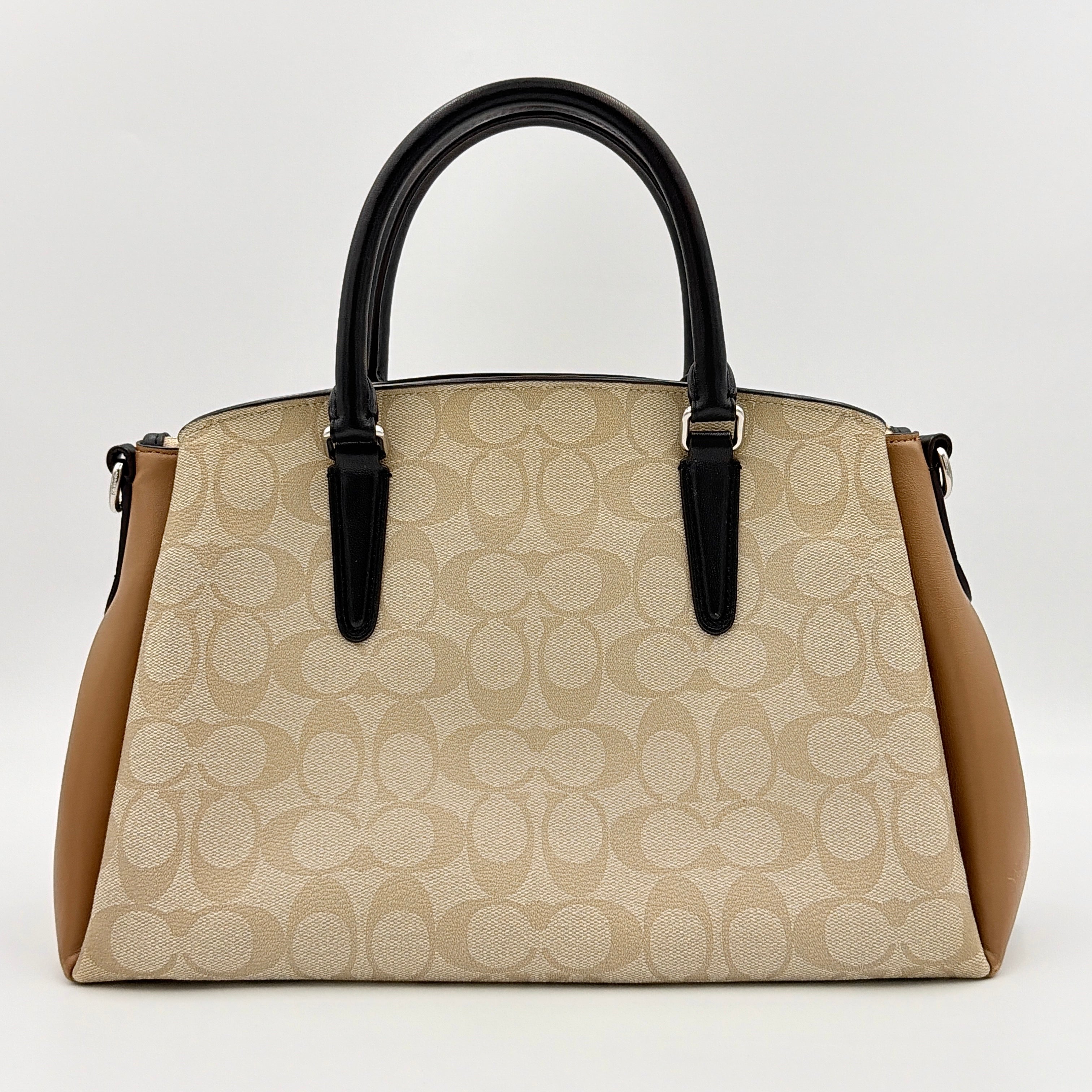 Coach Signature Sage Carryall in beige monogram canvas and tan leather with black handles, styled as an elegant, softly structured handbag.
