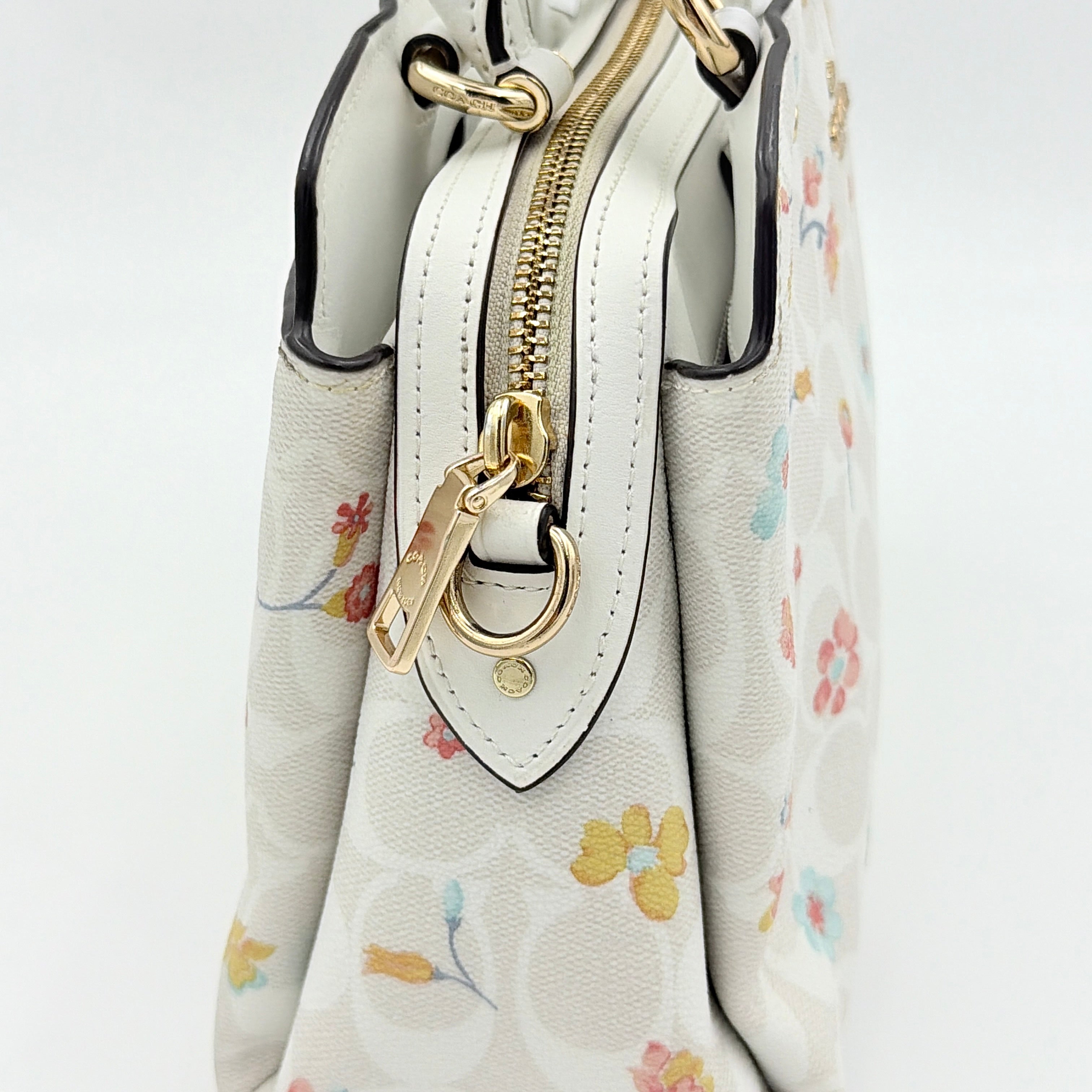 Coach 2Way Signature Lillie Carryall in white canvas with gold hardware and multicolour floral print, accompanied by a detachable white shoulder strap.