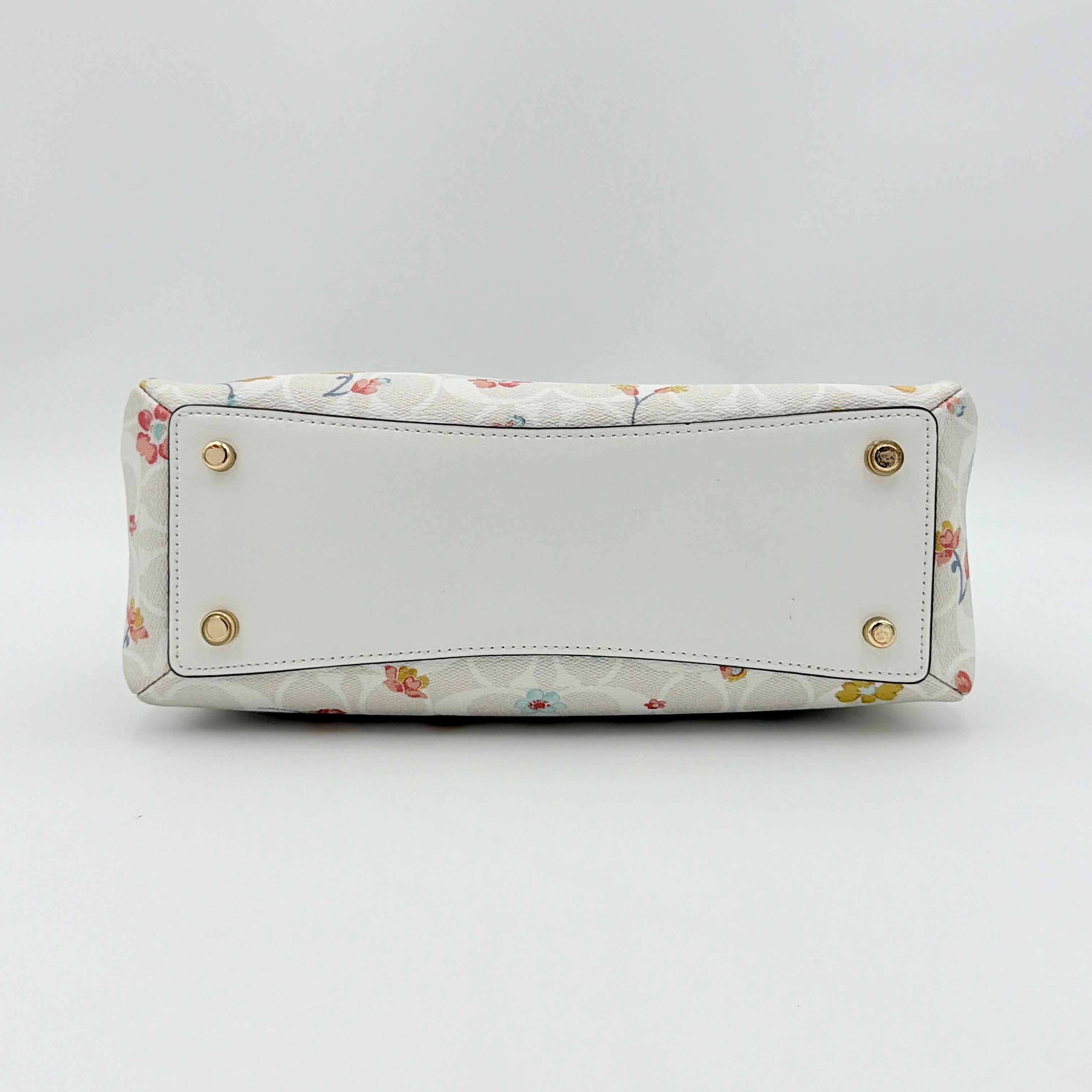 Coach 2Way Signature Lillie Carryall in white canvas with gold hardware and multicolour floral print, accompanied by a detachable white shoulder strap.
