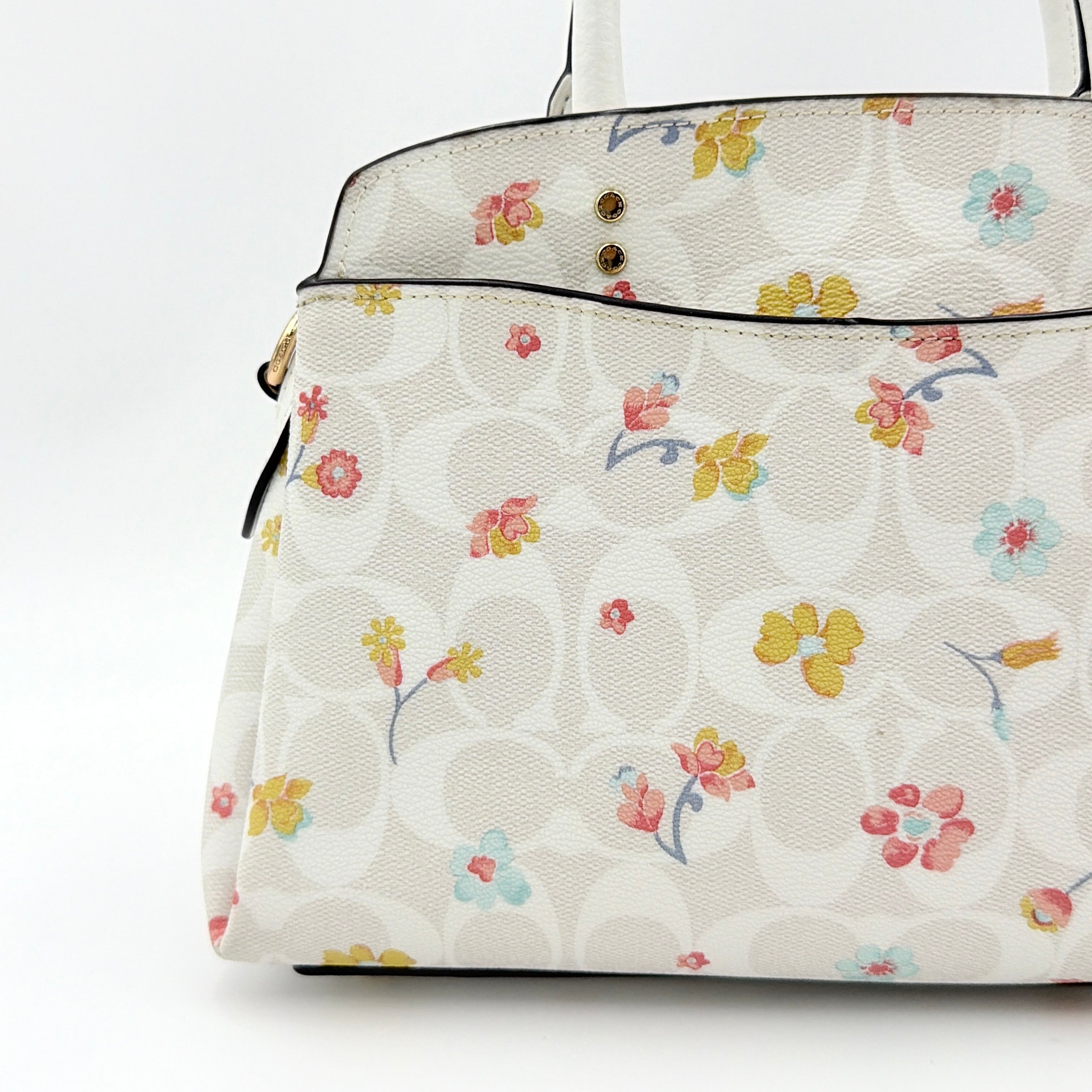 Coach 2Way Signature Lillie Carryall in white canvas with gold hardware and multicolour floral print, accompanied by a detachable white shoulder strap.