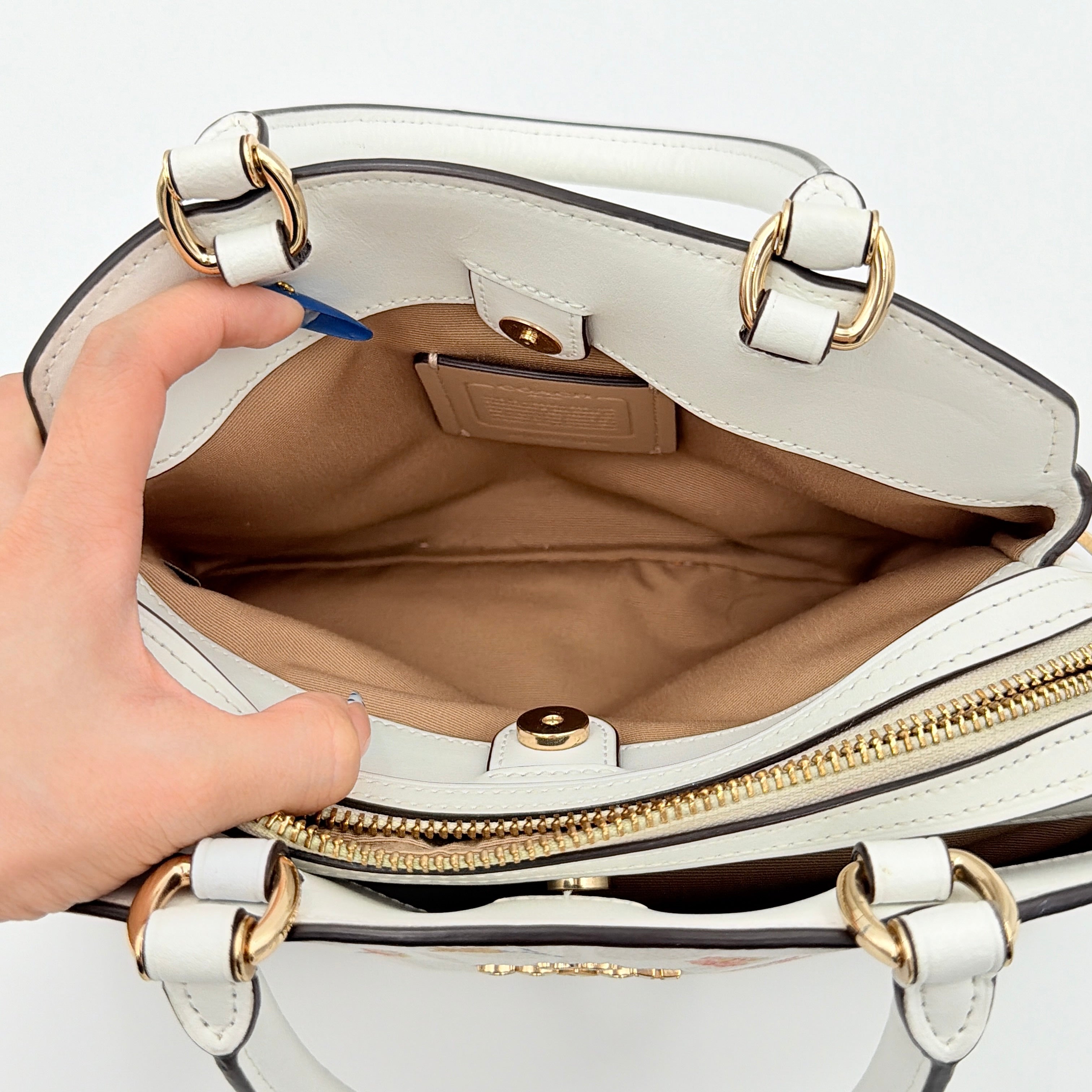 Coach 2Way Signature Lillie Carryall in white canvas with gold hardware and multicolour floral print, accompanied by a detachable white shoulder strap.