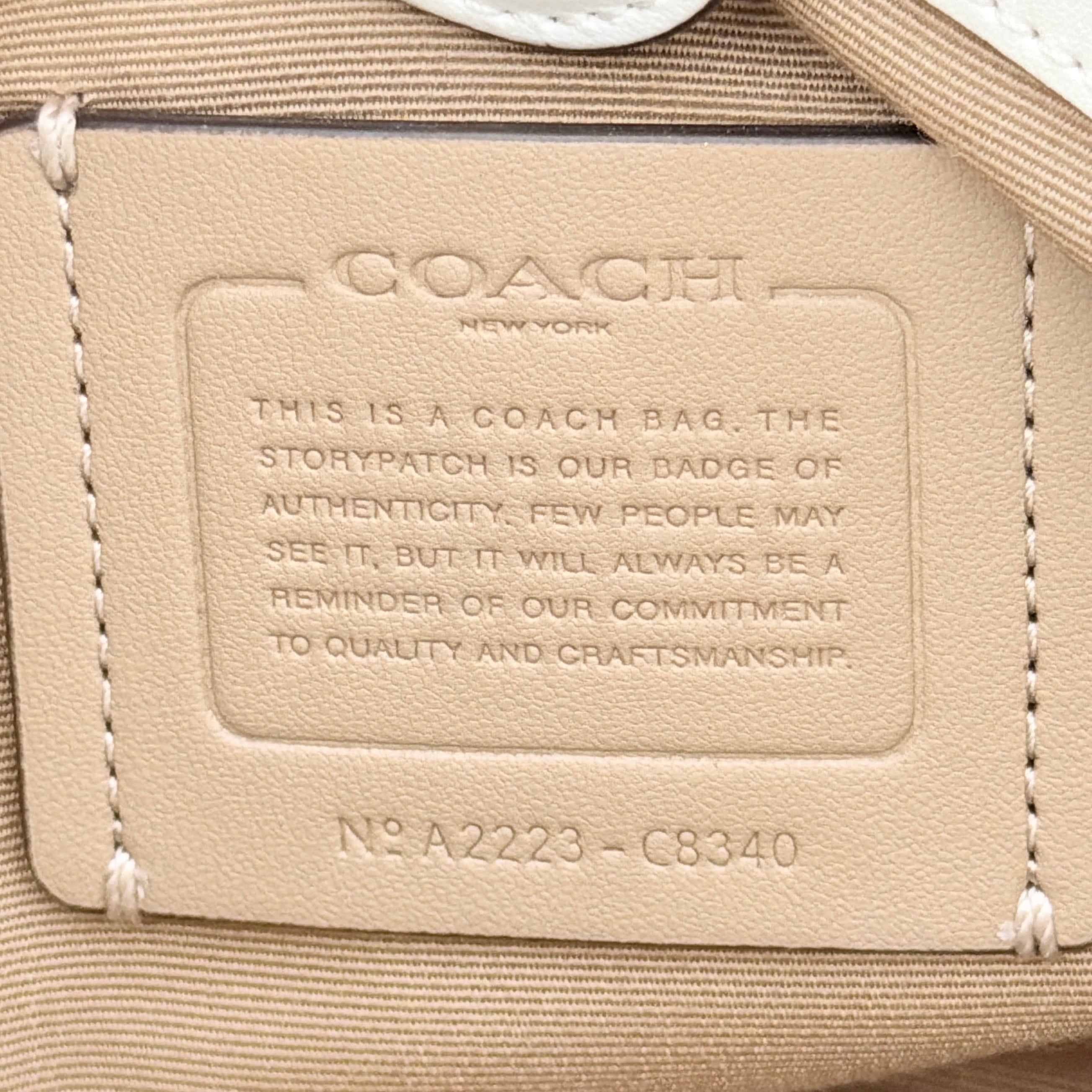 Coach 2Way Signature Lillie Carryall in white canvas with gold hardware and multicolour floral print, accompanied by a detachable white shoulder strap.