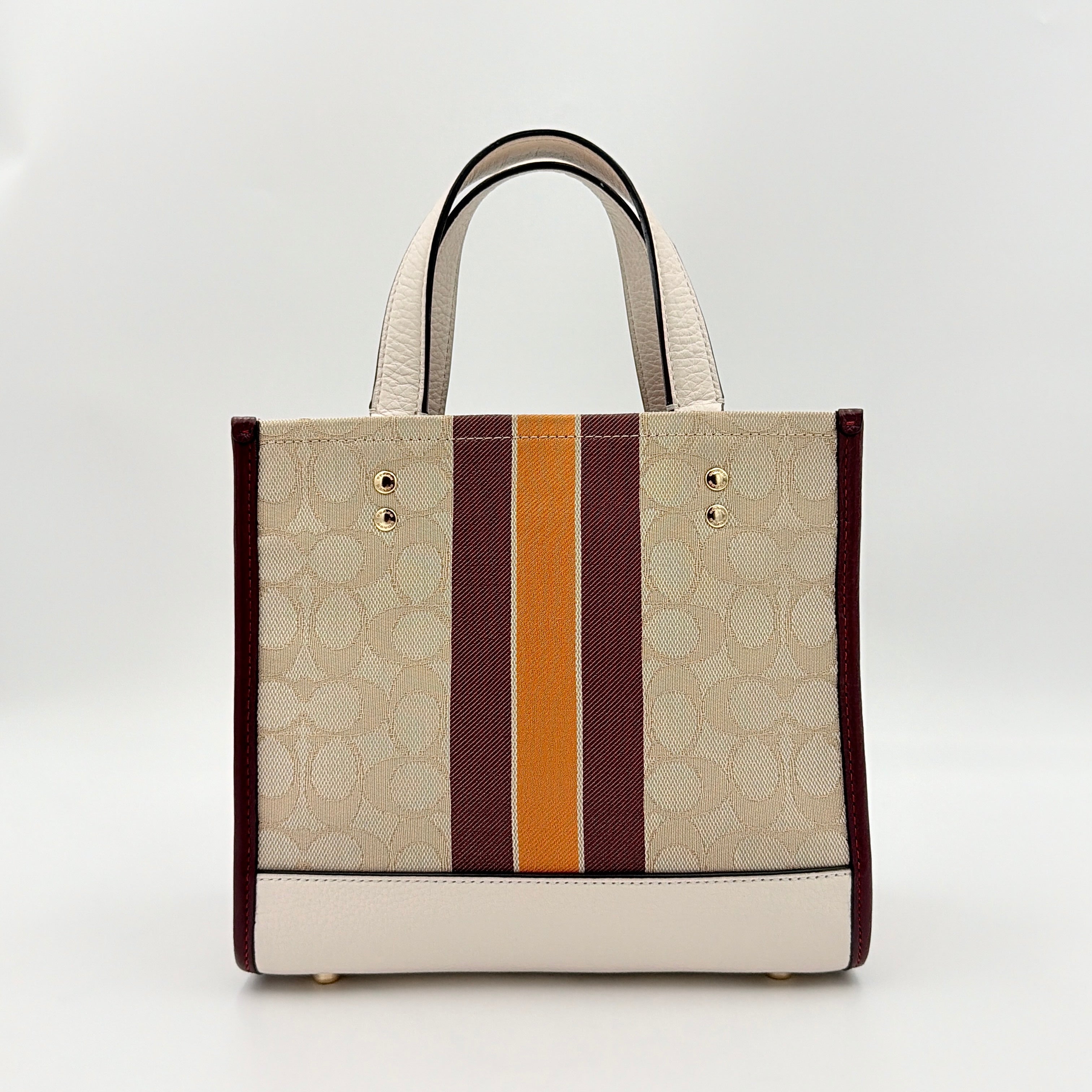 Coach Signature Dempsey 22 Stripe Tote Bag in beige canvas with bold vertical stripes, leather trims, logo patch, and detachable strap.