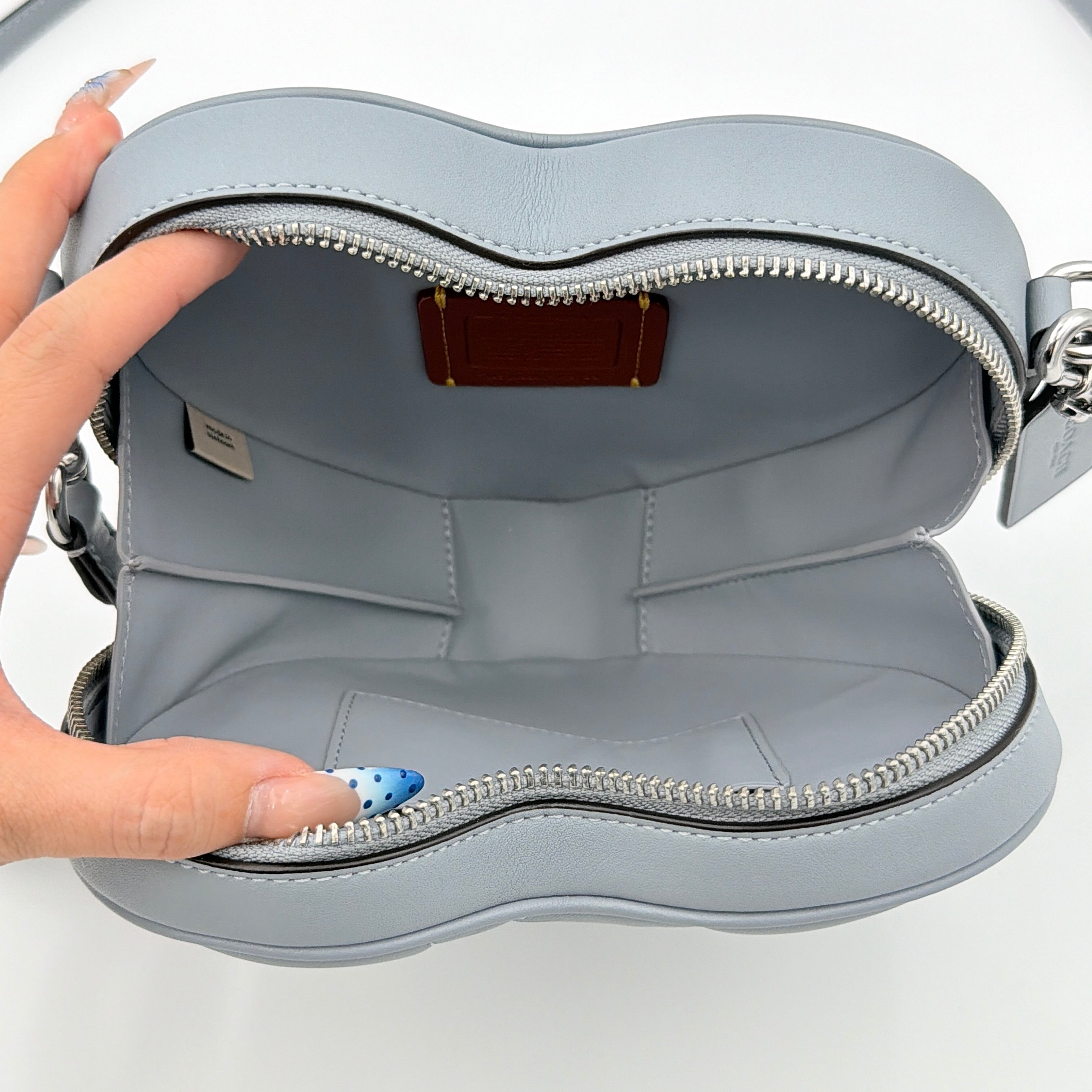 Coach heart-shaped quilted grey crossbody bag with silver hardware and adjustable strap.