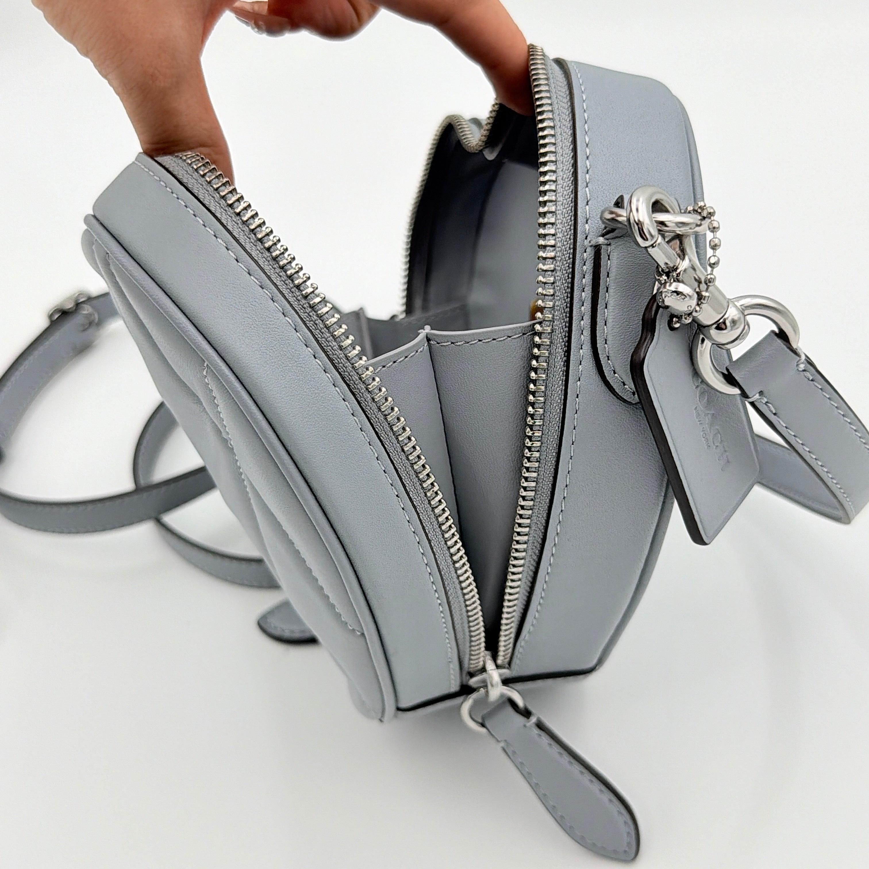 Coach heart-shaped quilted grey crossbody bag with silver hardware and adjustable strap.