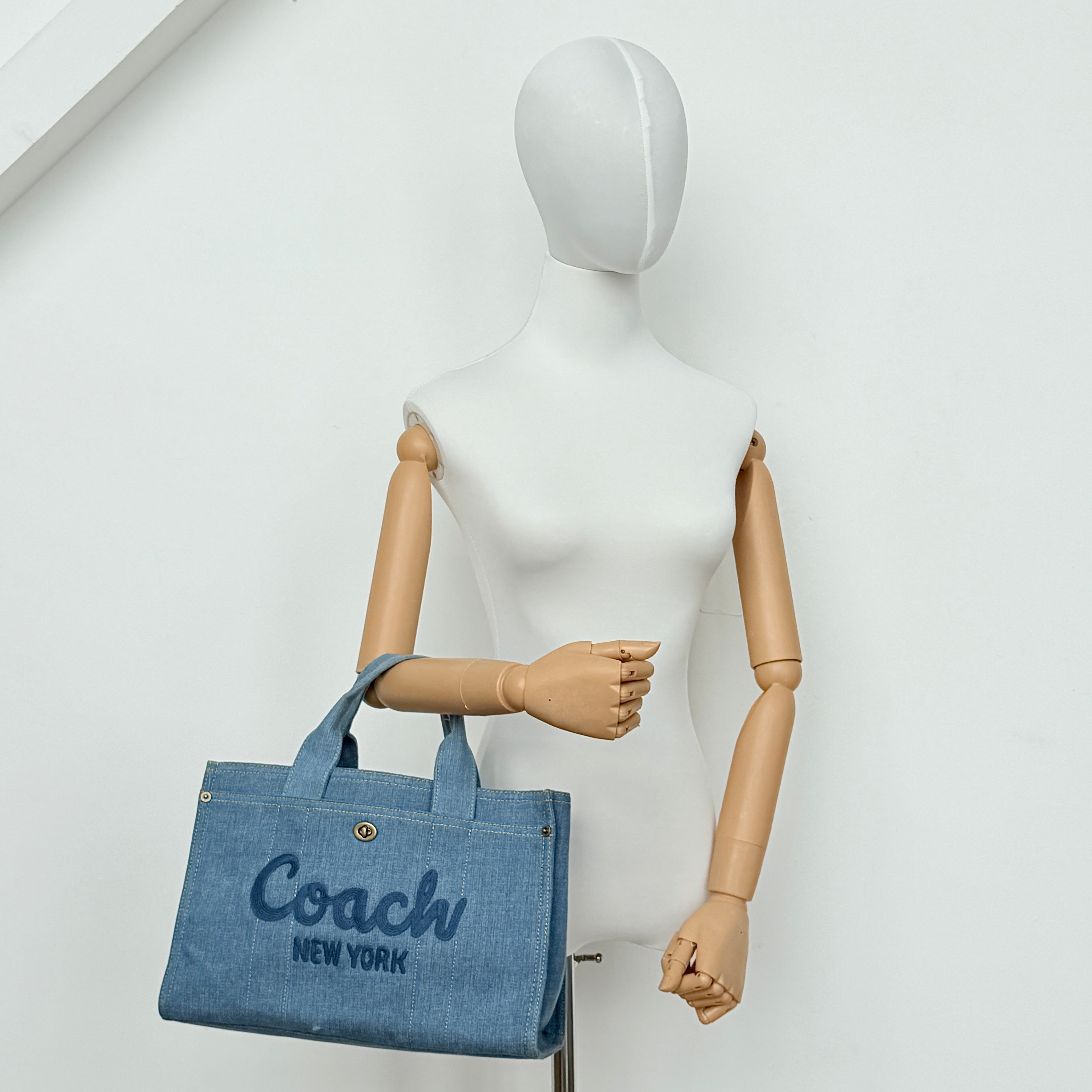 Coach denim 2Way Logo 20 Tote Bag in blue, embroidered with 'Coach New York', shown with detachable navy strap.