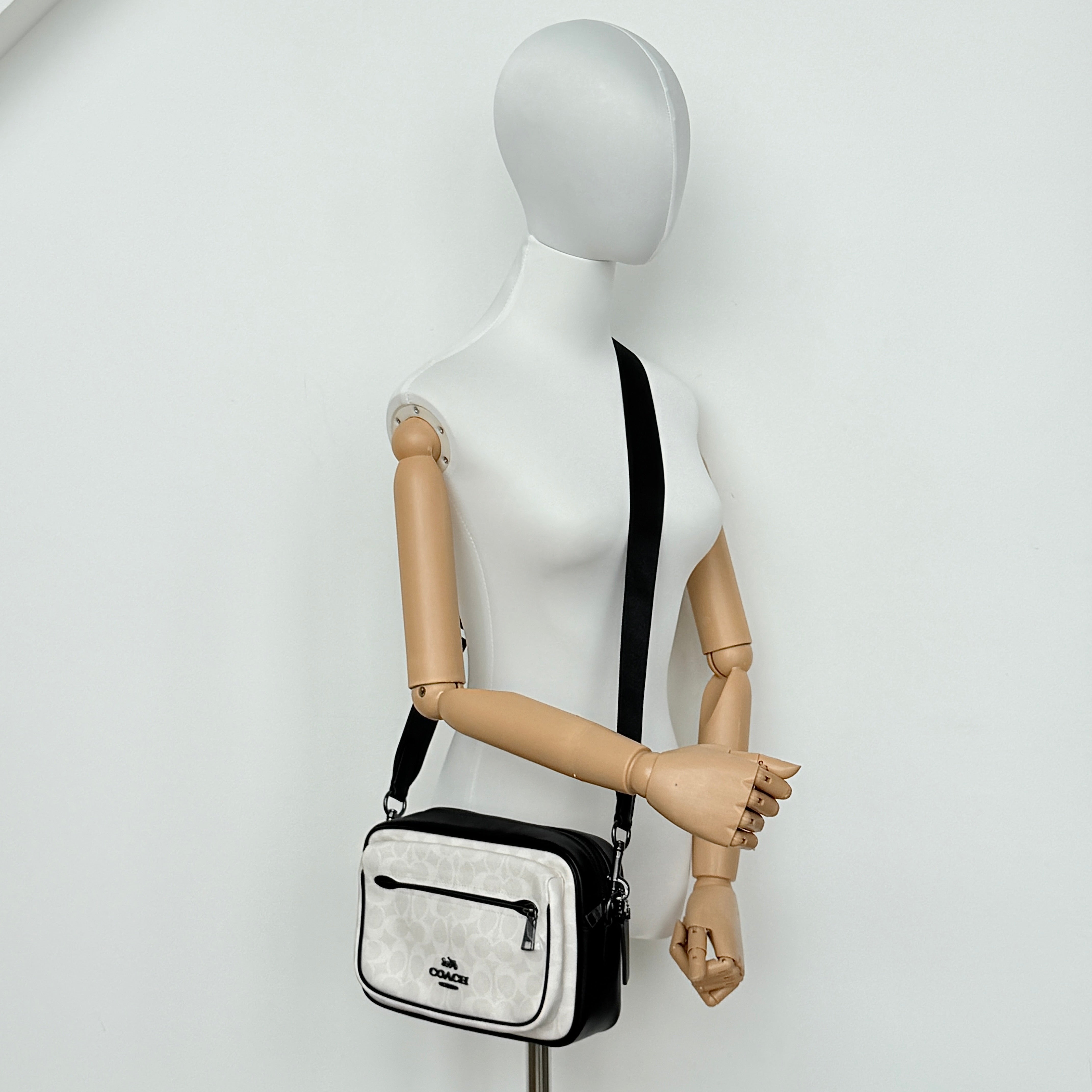 Coach Signature Elias Crossbody Bag in white canvas with black leather trim and silver hardware, styled with an adjustable black strap.