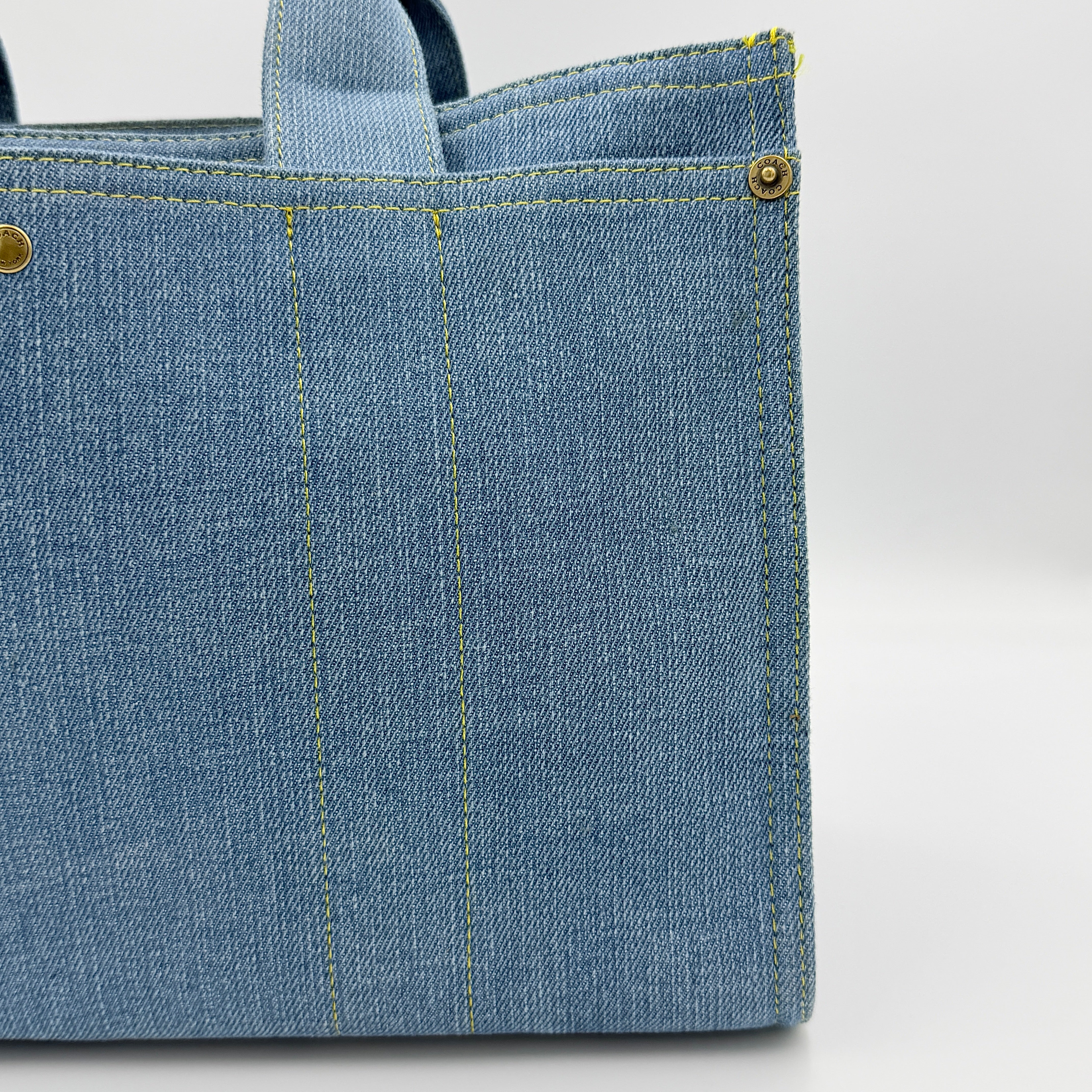 Coach denim 2Way Logo 20 Tote Bag in blue, embroidered with 'Coach New York', shown with detachable navy strap.