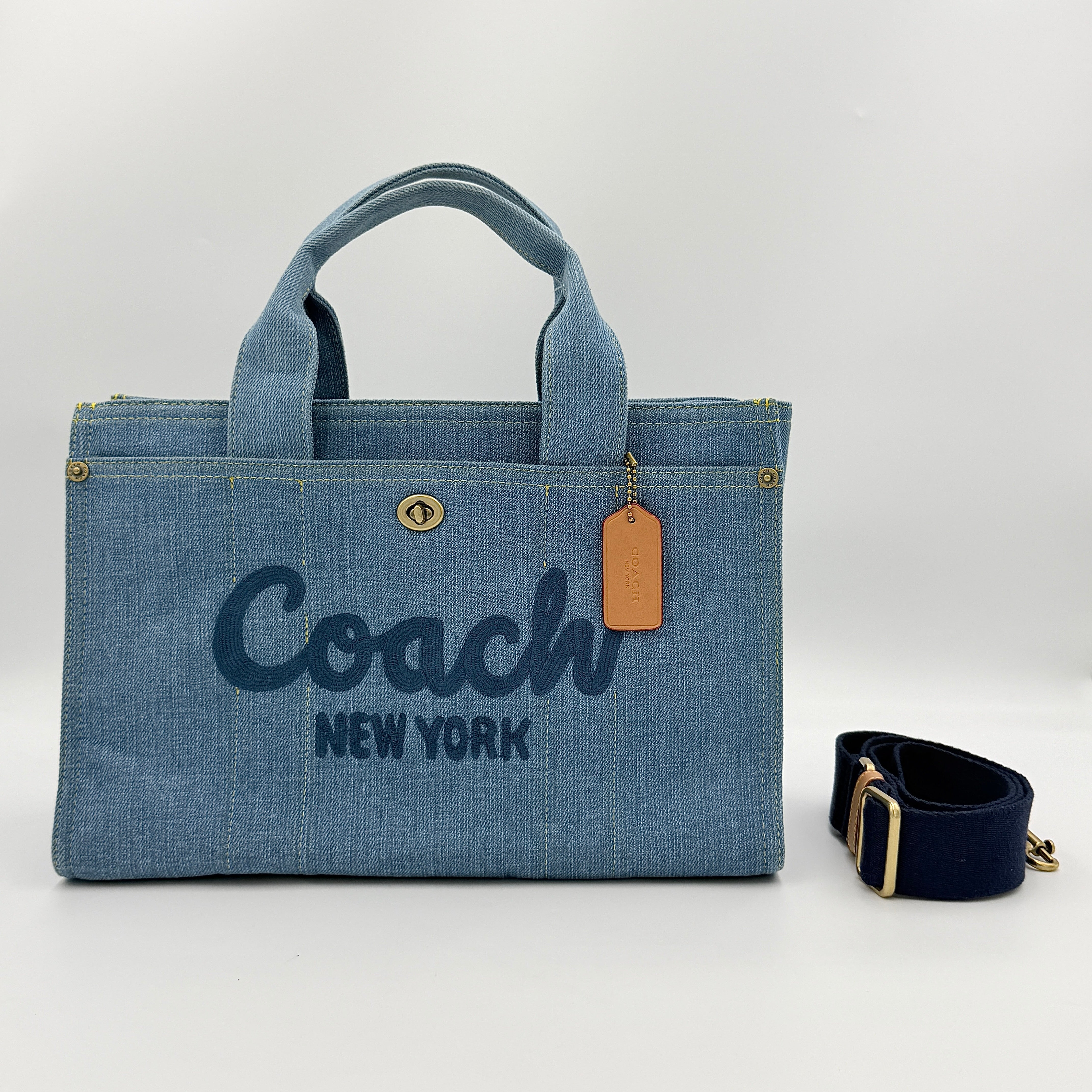 Coach denim 2Way Logo 20 Tote Bag in blue, embroidered with 'Coach New York', shown with detachable navy strap.