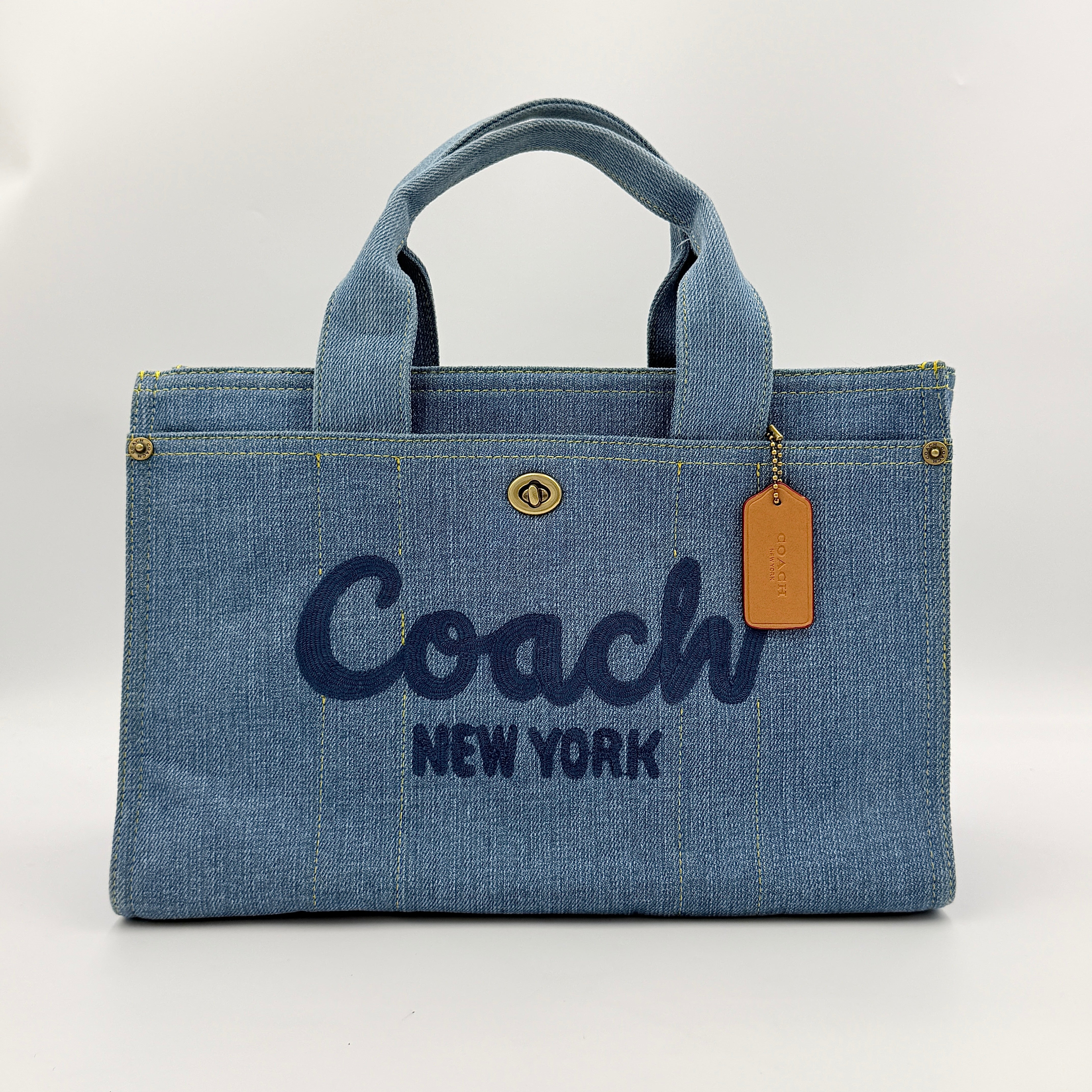 Coach denim 2Way Logo 20 Tote Bag in blue, embroidered with 'Coach New York', shown with detachable navy strap.
