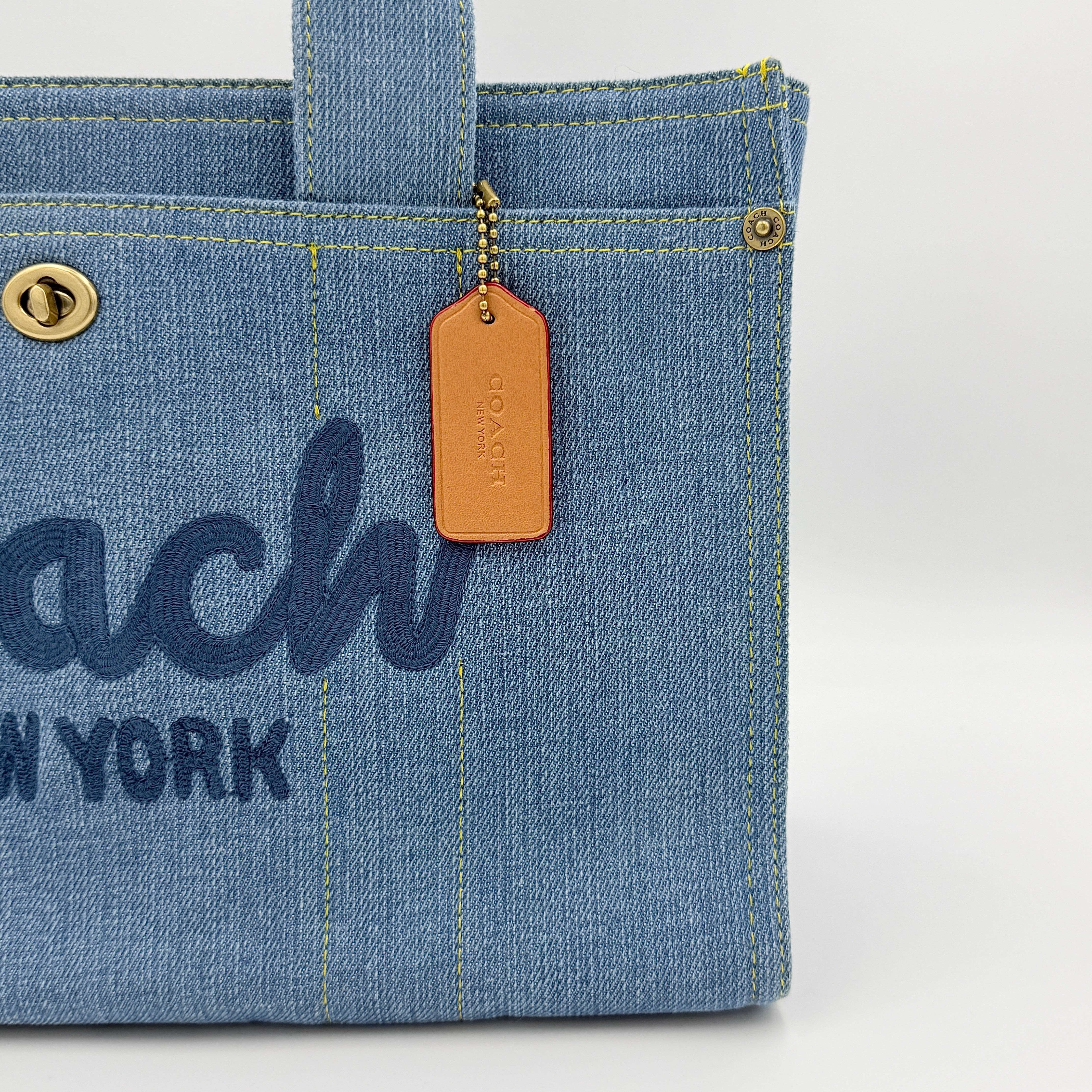 Coach denim 2Way Logo 20 Tote Bag in blue, embroidered with 'Coach New York', shown with detachable navy strap.