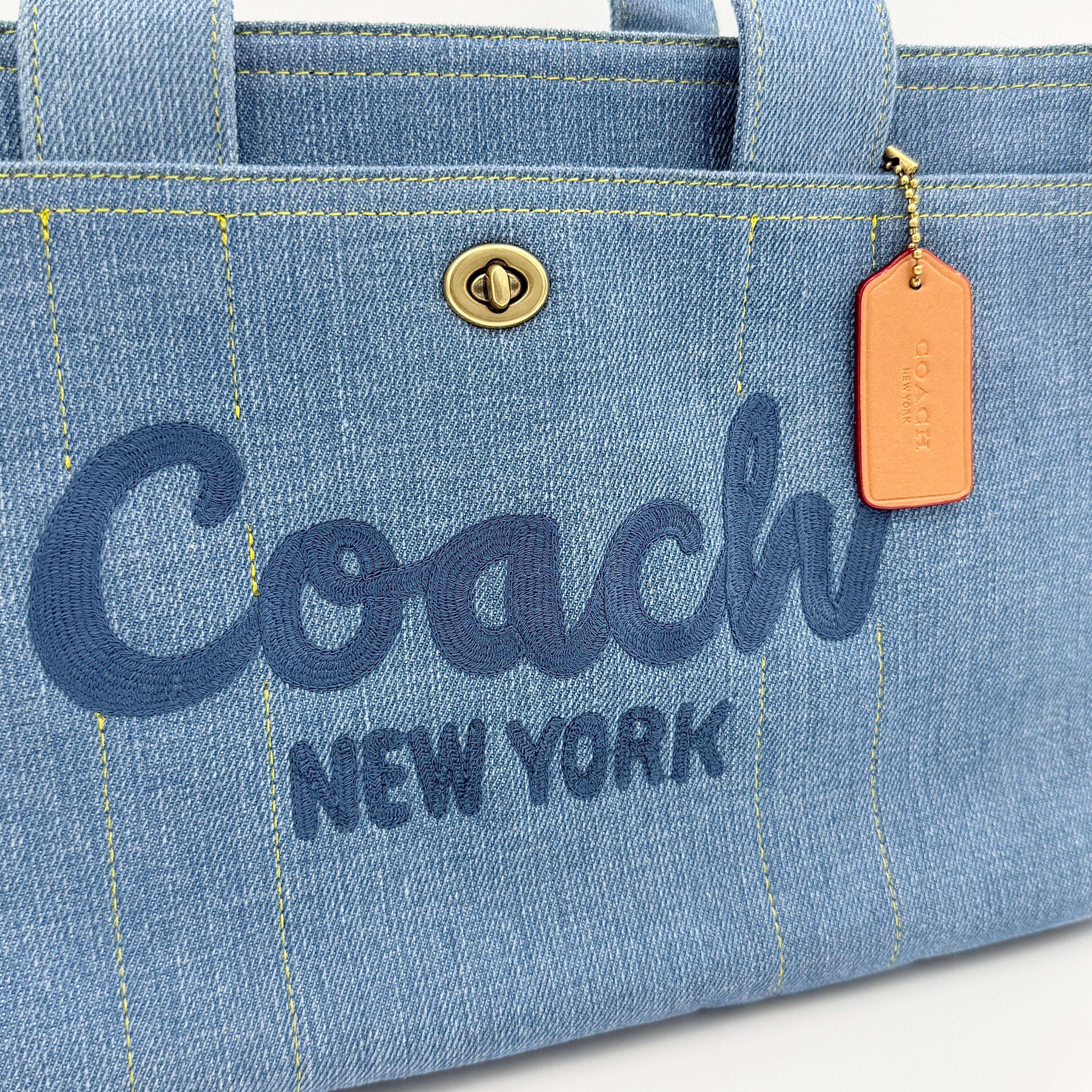 Coach denim 2Way Logo 20 Tote Bag in blue, embroidered with 'Coach New York', shown with detachable navy strap.