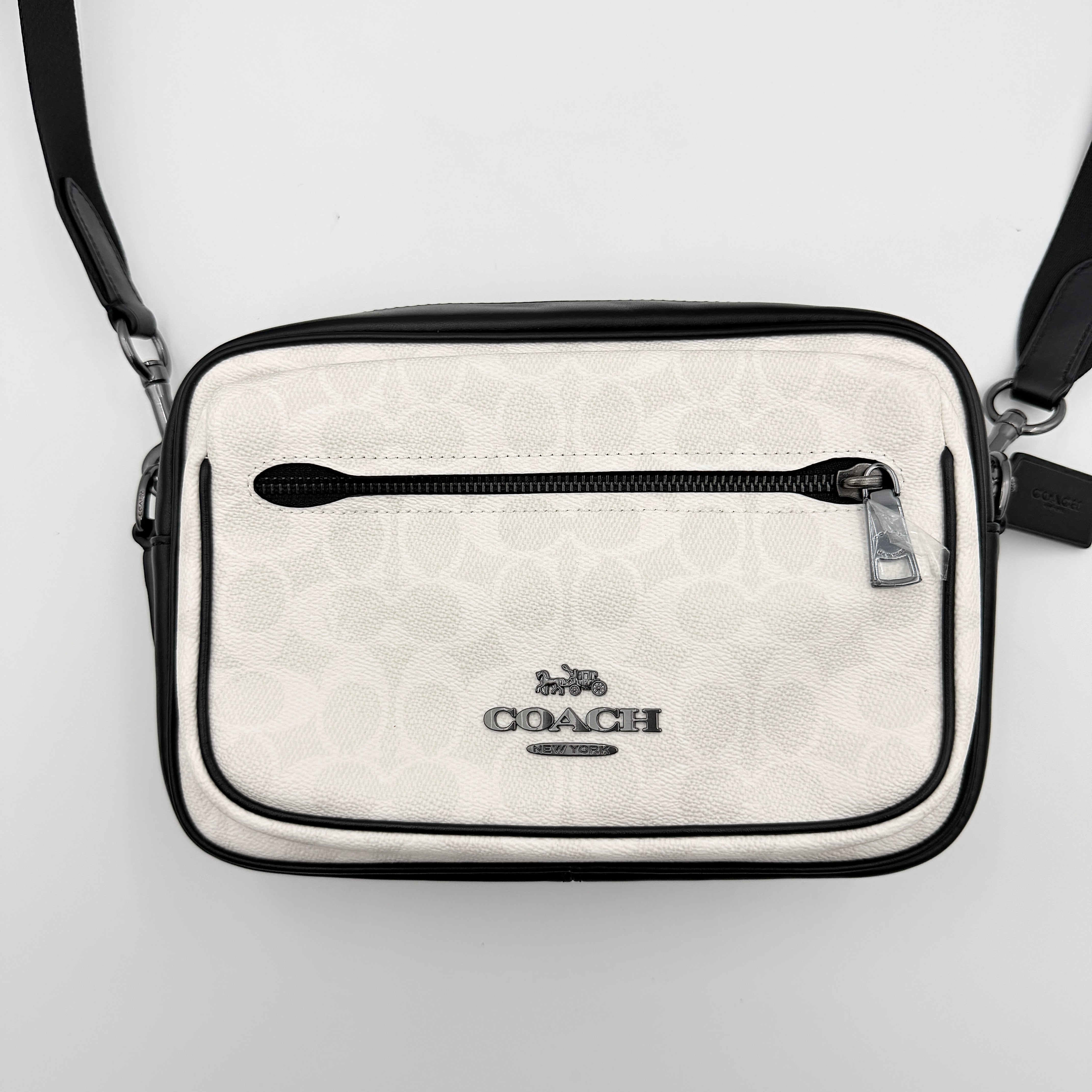 Coach Signature Elias Crossbody Bag in white canvas with black leather trim and silver hardware, styled with an adjustable black strap.