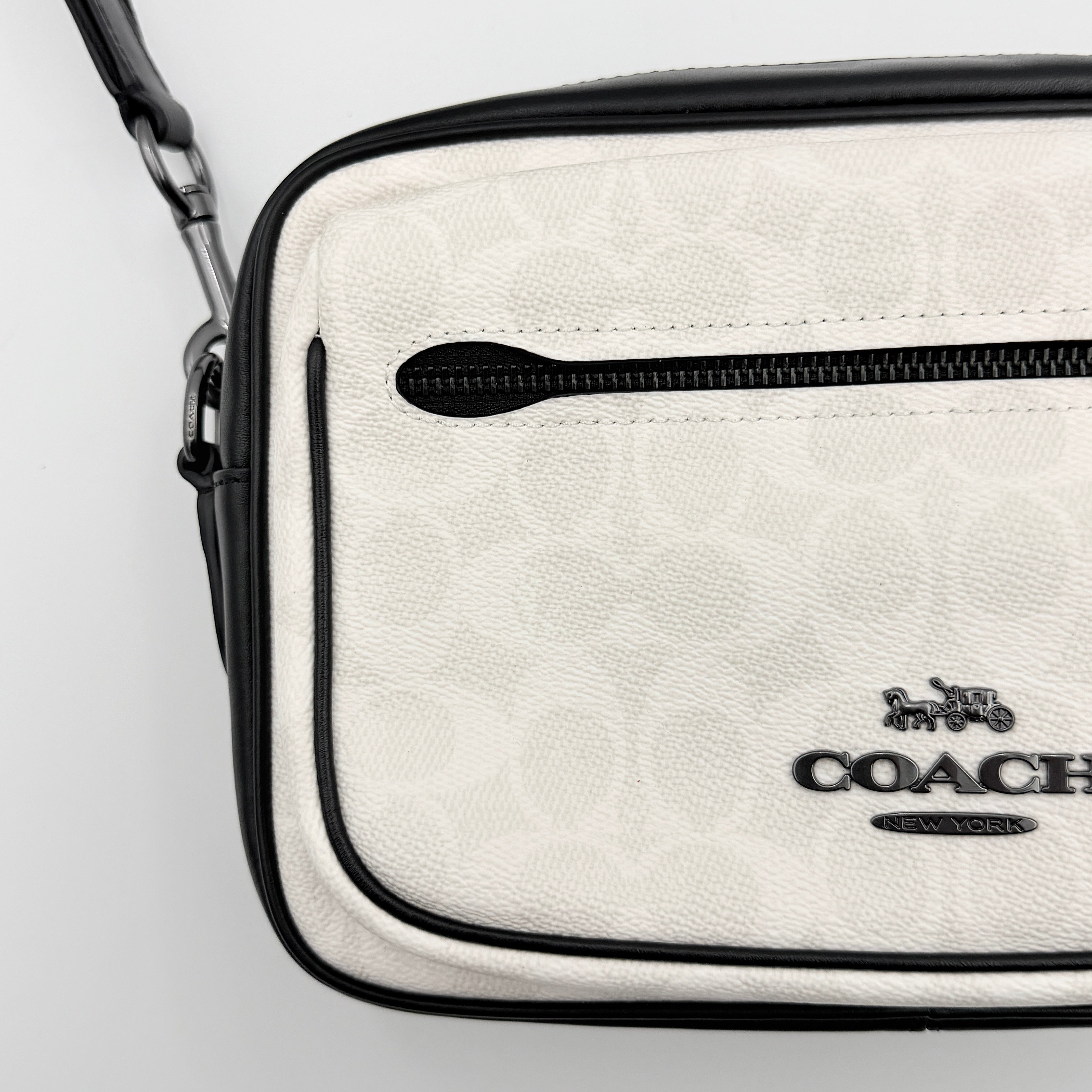 Coach Signature Elias Crossbody Bag in white canvas with black leather trim and silver hardware, styled with an adjustable black strap.