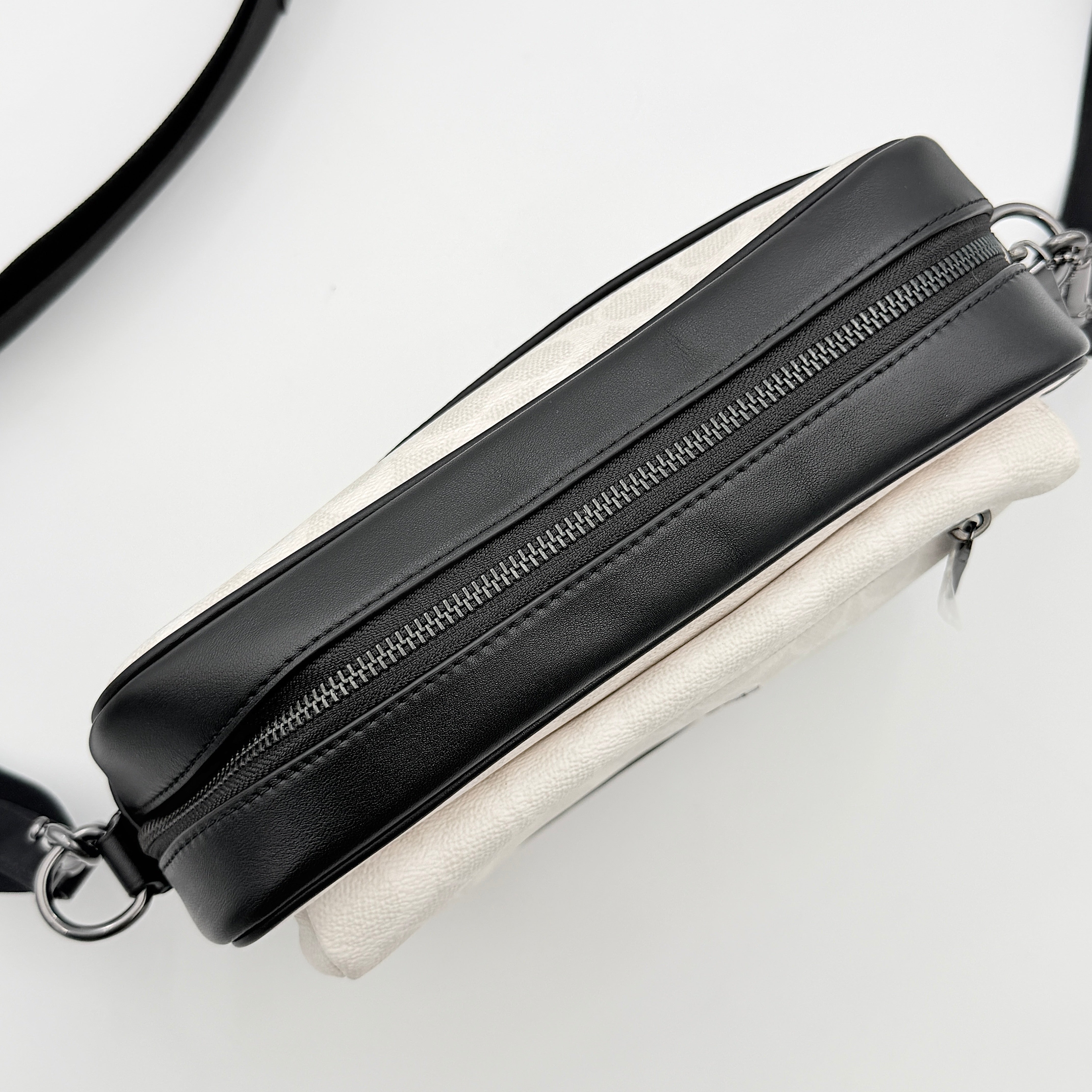 Coach Signature Elias Crossbody Bag in white canvas with black leather trim and silver hardware, styled with an adjustable black strap.