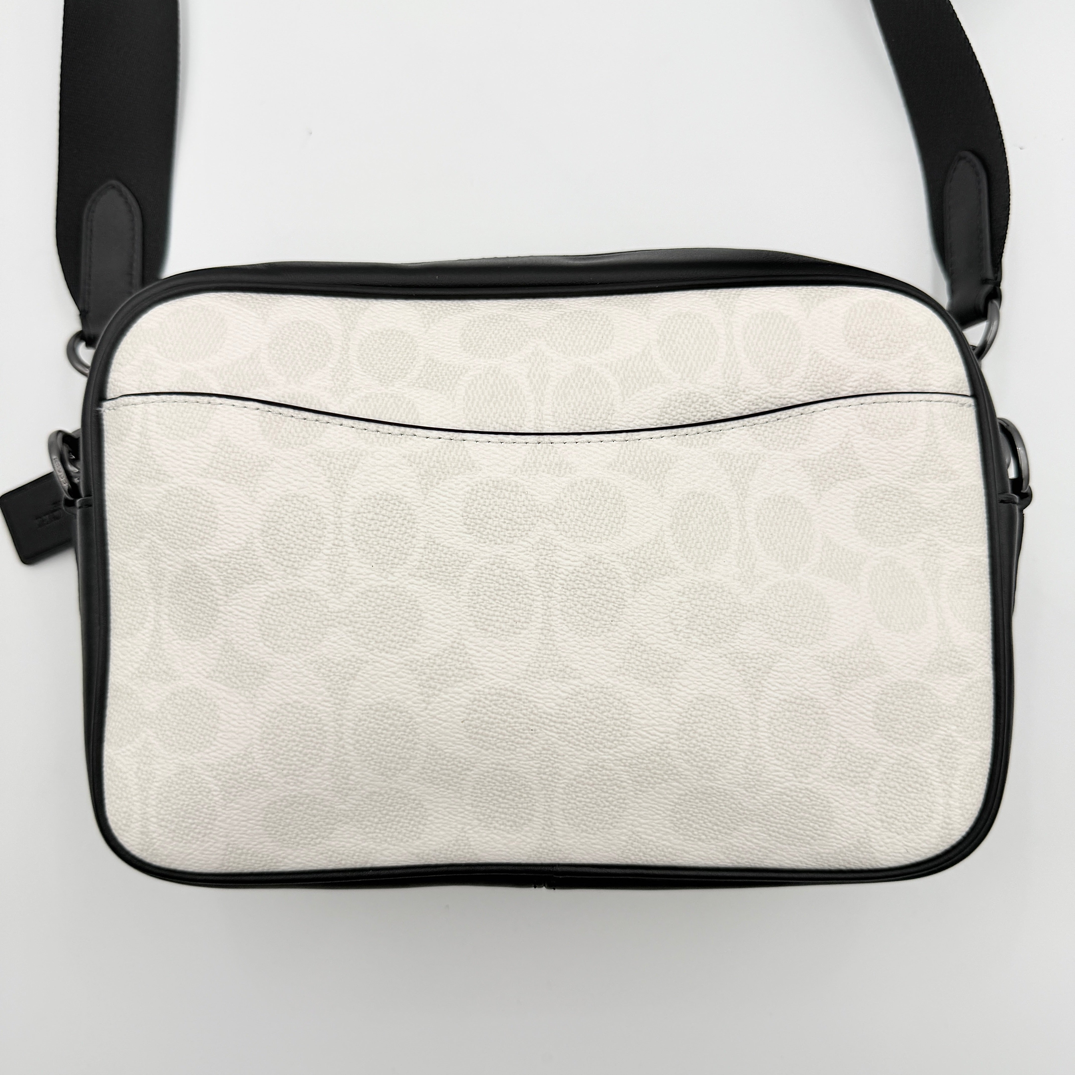 Coach Signature Elias Crossbody Bag in white canvas with black leather trim and silver hardware, styled with an adjustable black strap.