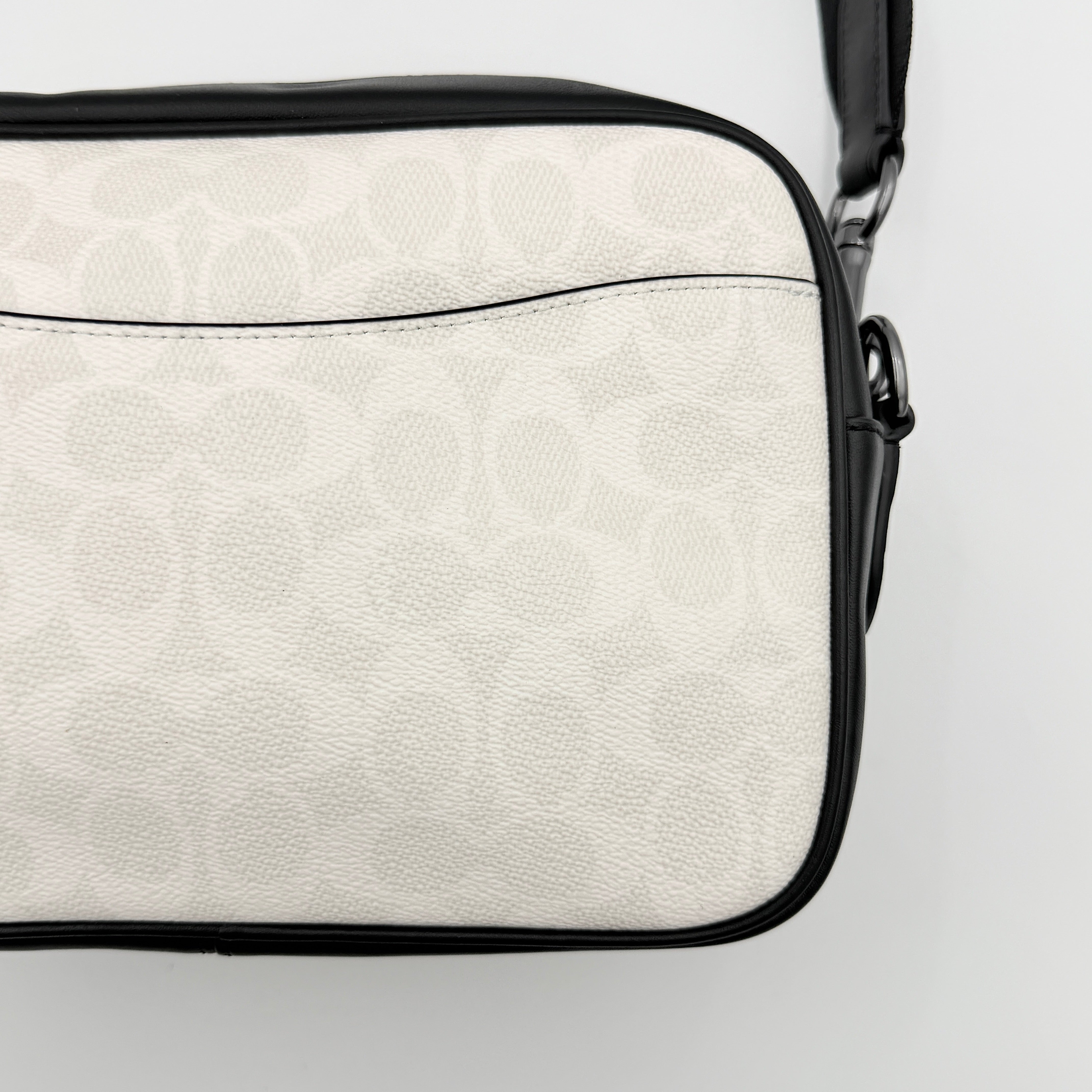 Coach Signature Elias Crossbody Bag in white canvas with black leather trim and silver hardware, styled with an adjustable black strap.