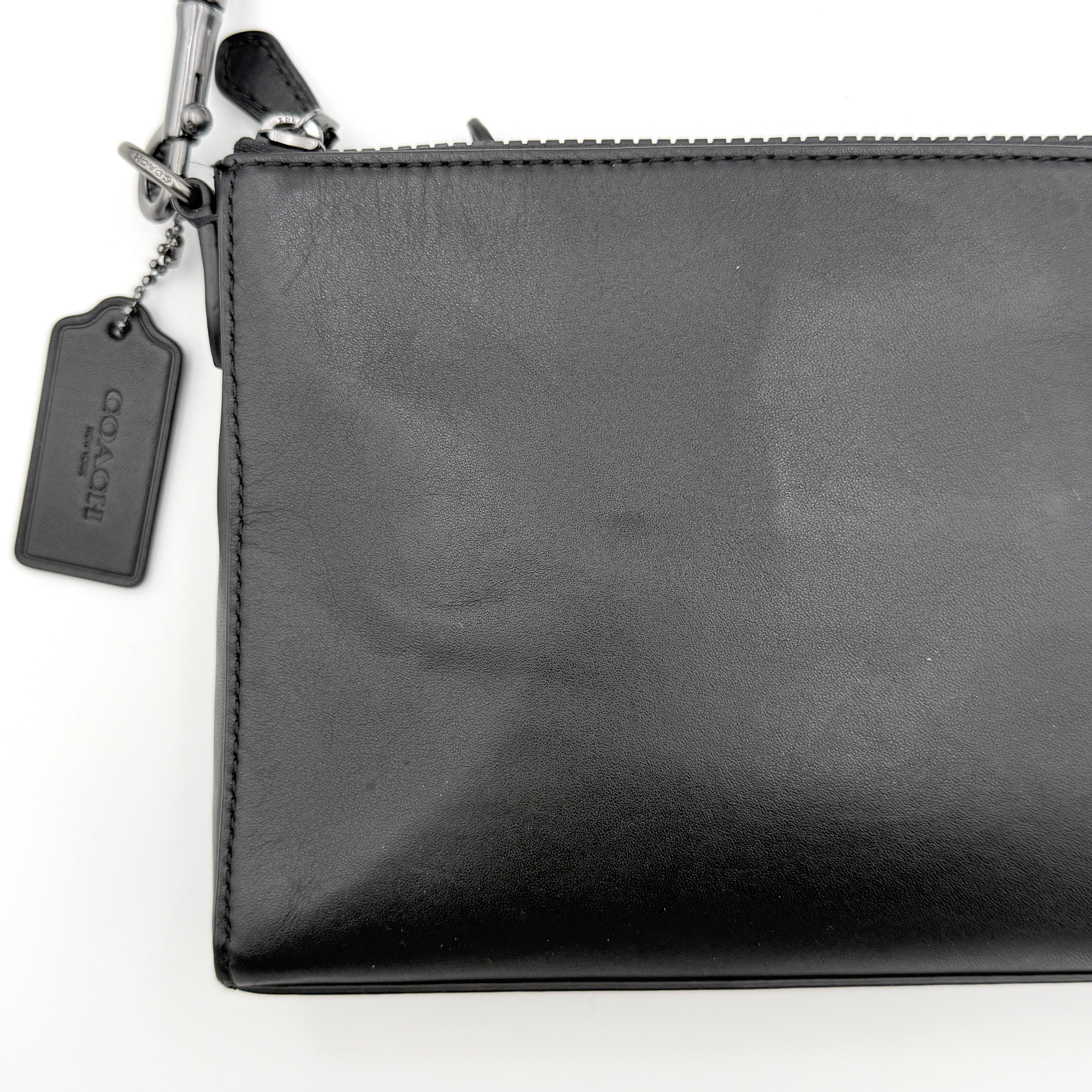 Coach Signature Holden Crossbody Bag in black with beige round coin pouch, featuring coated canvas and leather panels against a white background.