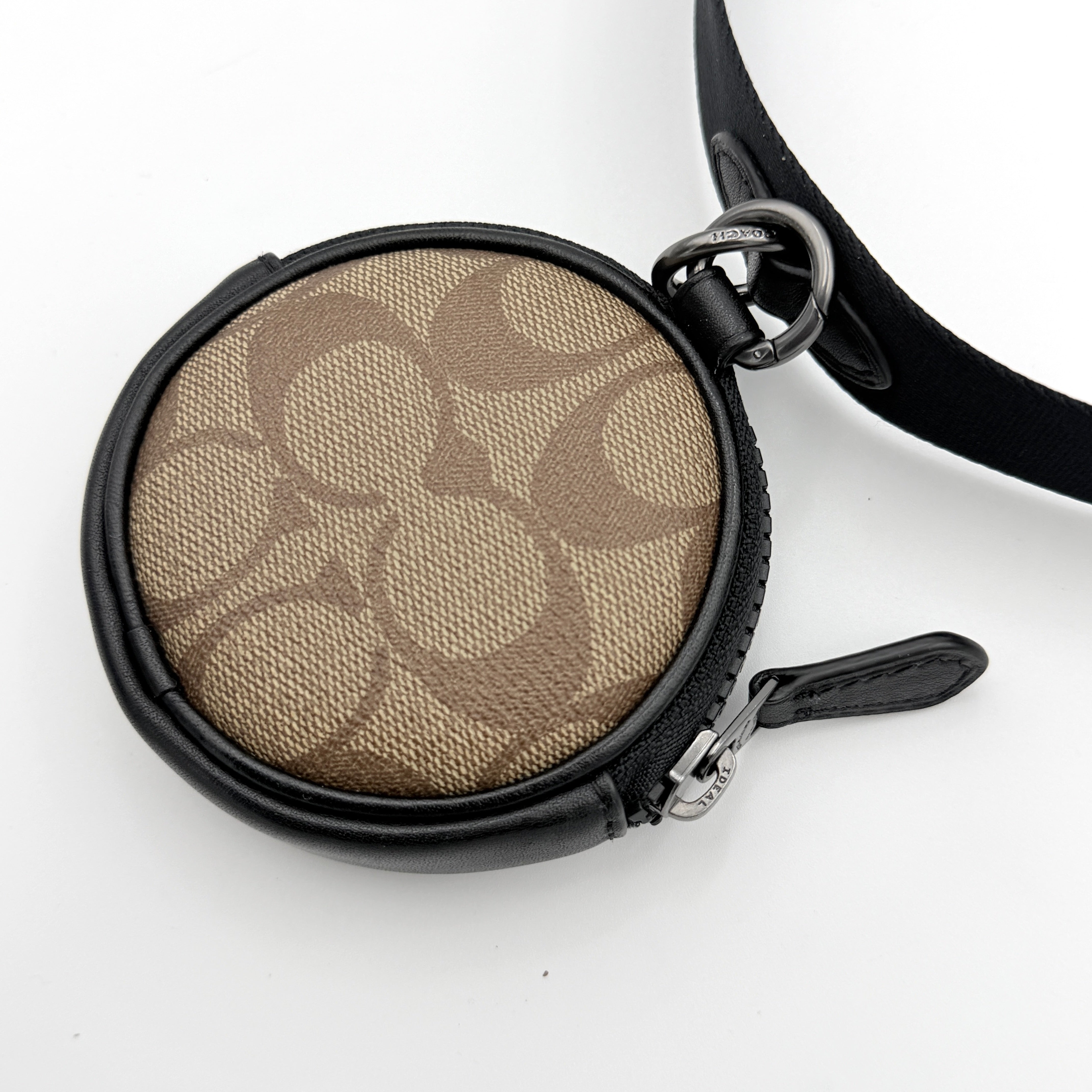 Coach Signature Holden Crossbody Bag in black with beige round coin pouch, featuring coated canvas and leather panels against a white background.