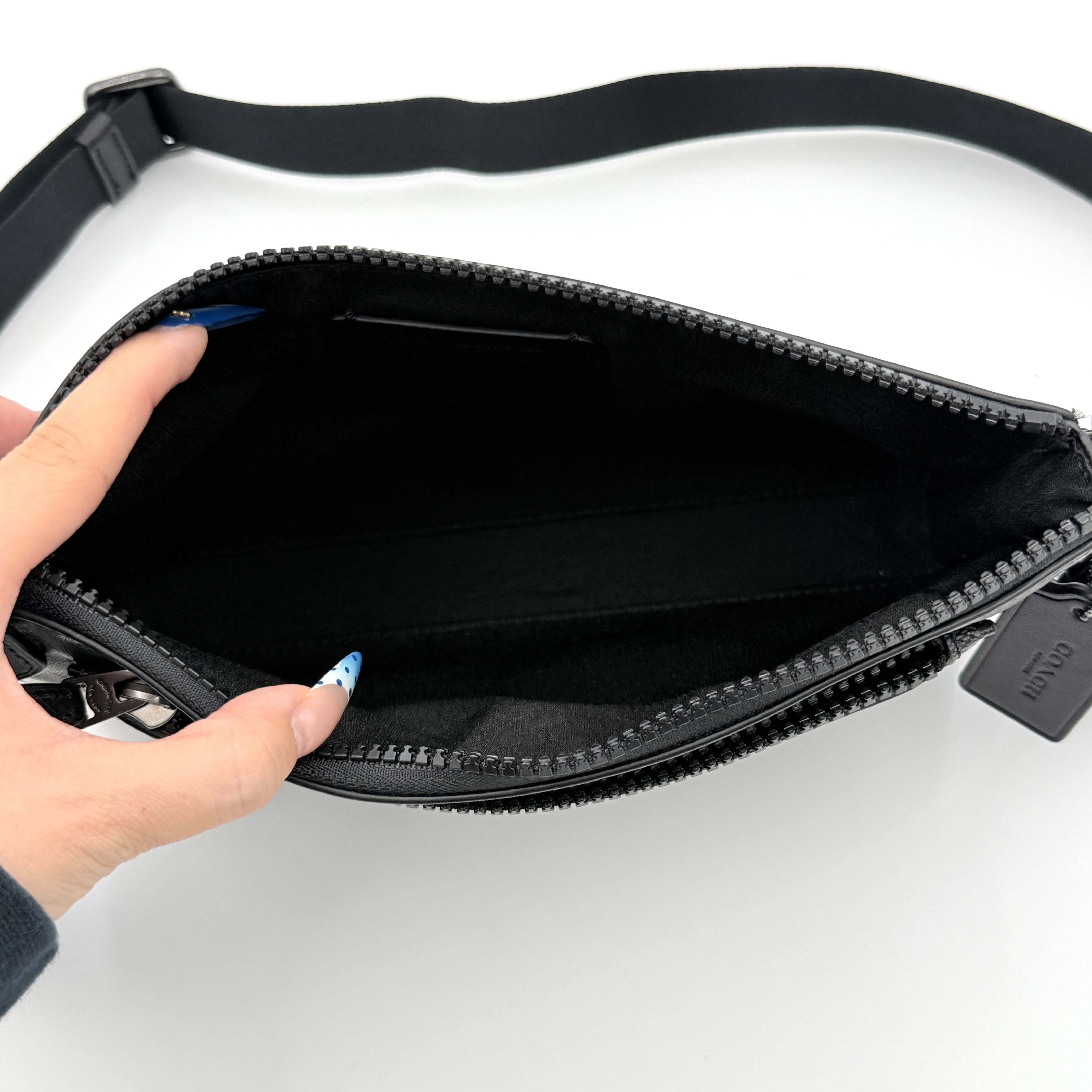 Coach Signature Holden Crossbody Bag in black with beige round coin pouch, featuring coated canvas and leather panels against a white background.