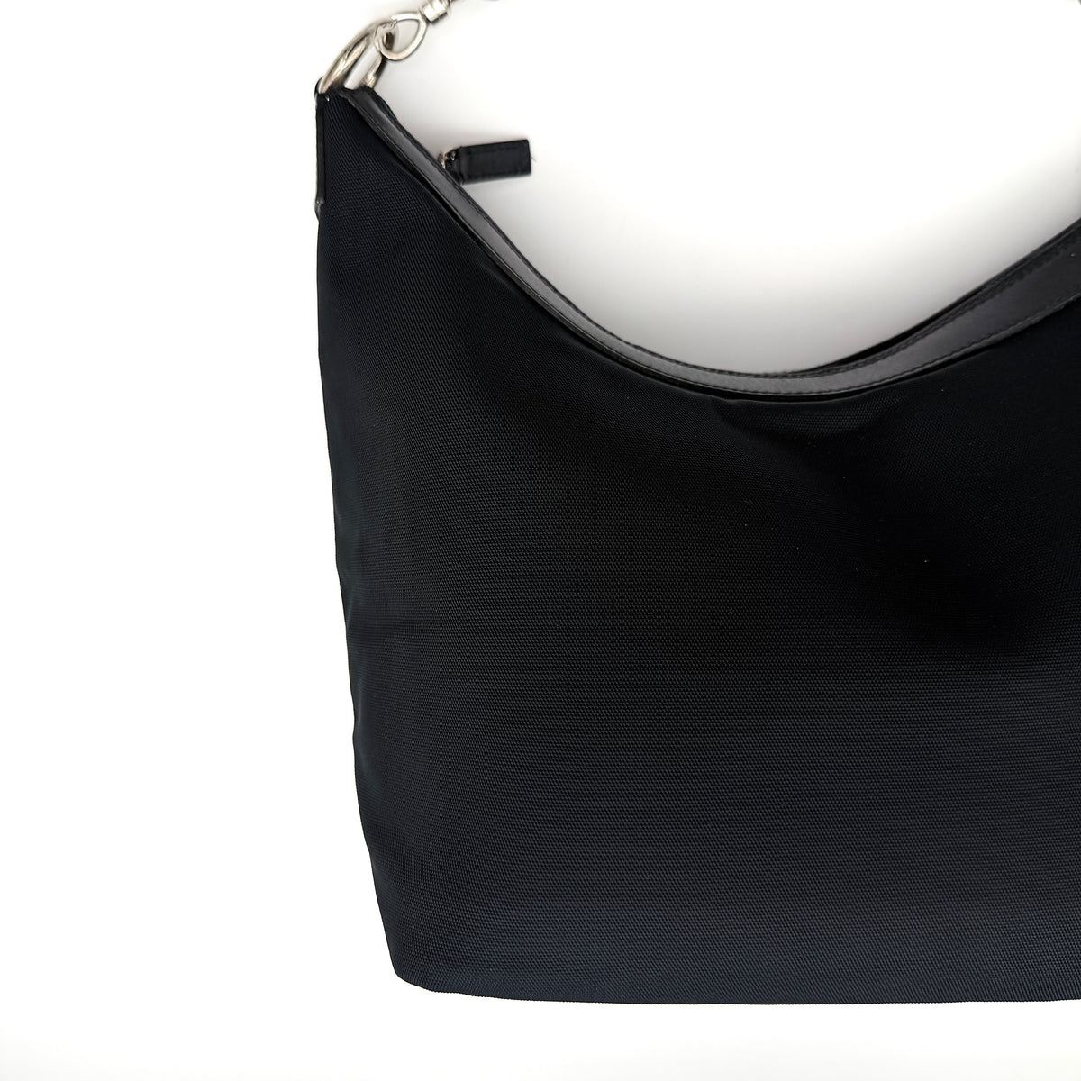Gucci black nylon shoulder bag with bamboo handle and silver-tone hardware against a white background.