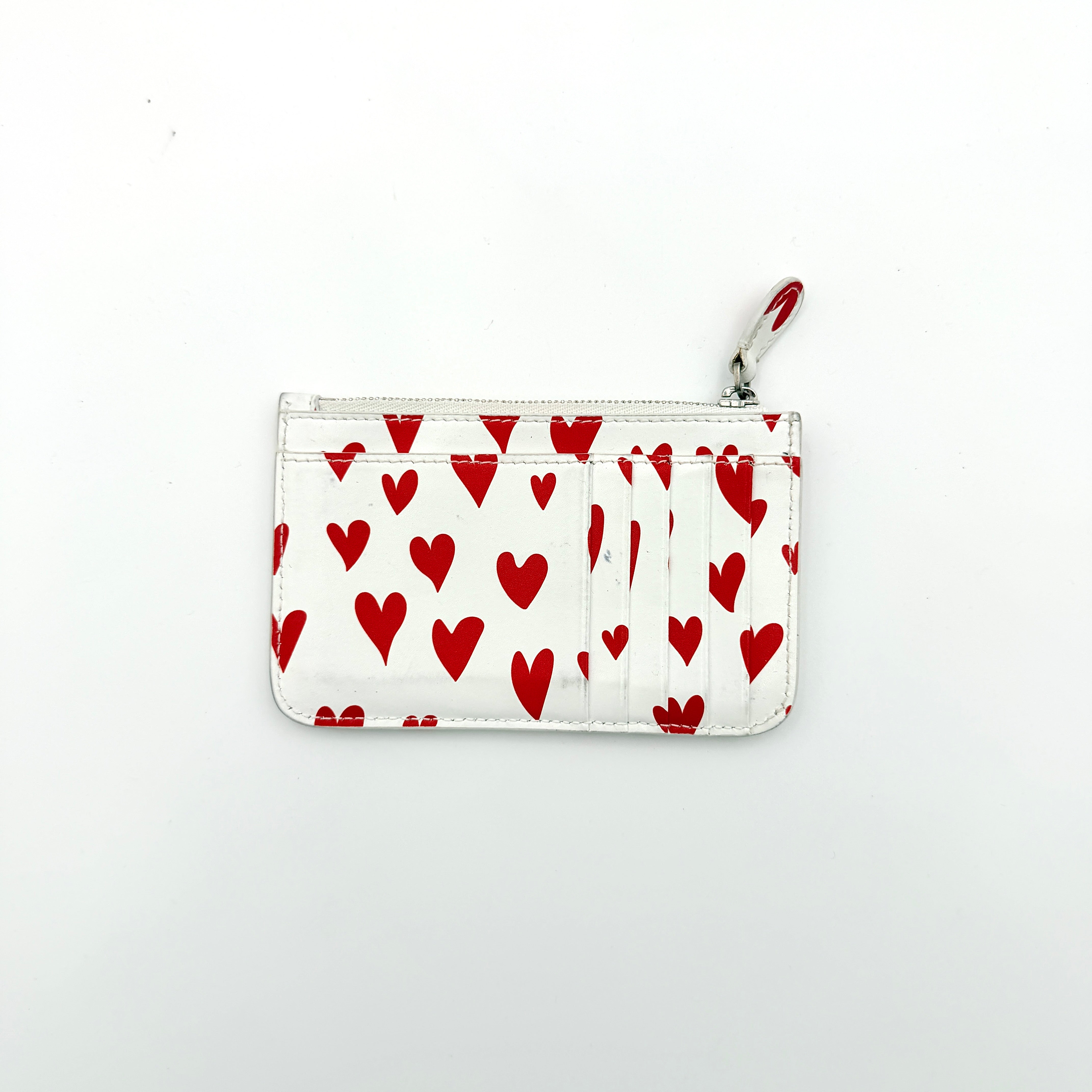 Balenciaga white leather card holder with playful red hearts and zip closure, set against a clean background.
