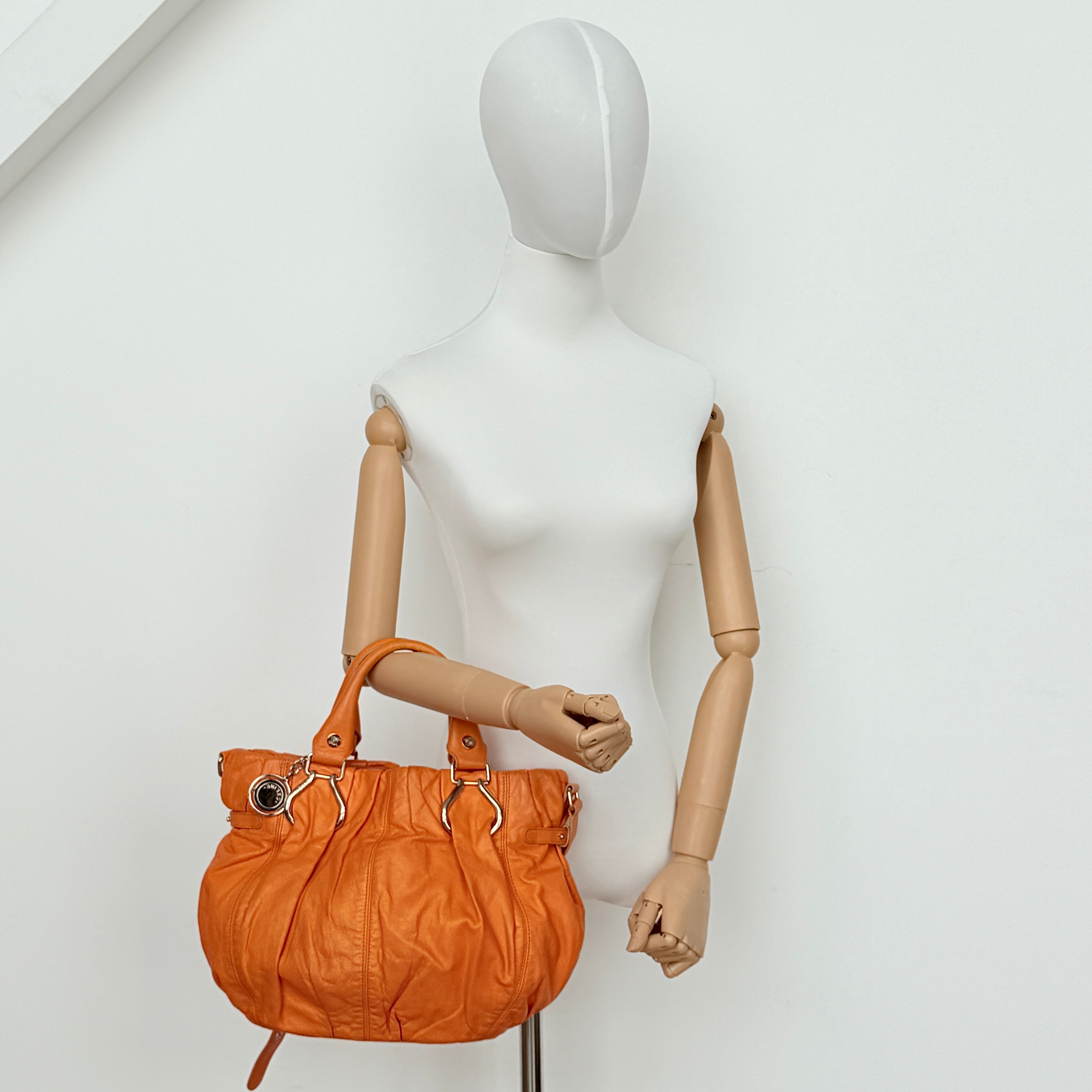 Celine 2Way Shoulder Bag in vibrant orange leather with silver-tone hardware and pleated detailing, shown with both top handles and an adjustable strap.