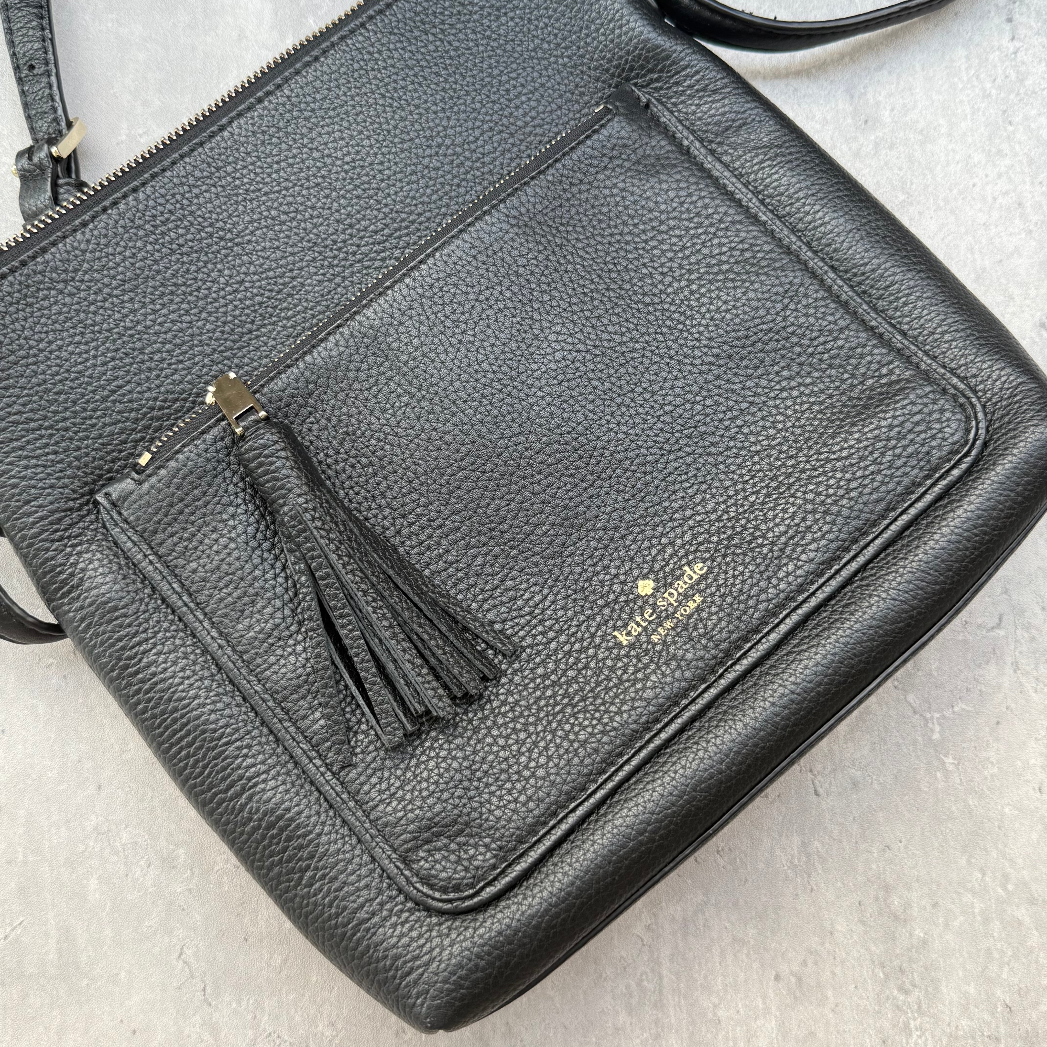 Kate Spade New York black pebbled leather crossbody bag with tassel zip pocket and gold-tone hardware