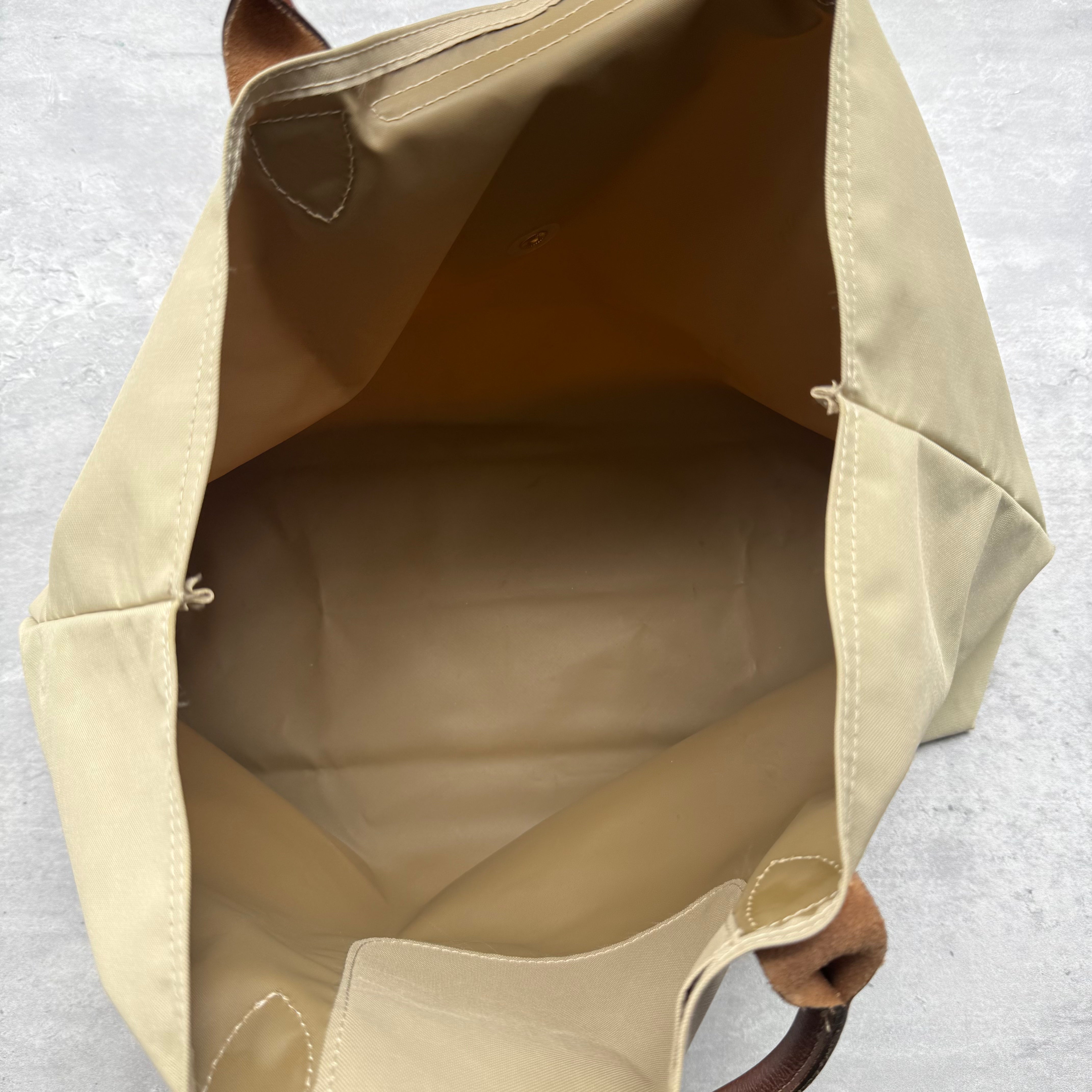 Longchamp Le Pliage Tote Bag in beige nylon with brown leather handles and gold-tone hardware.