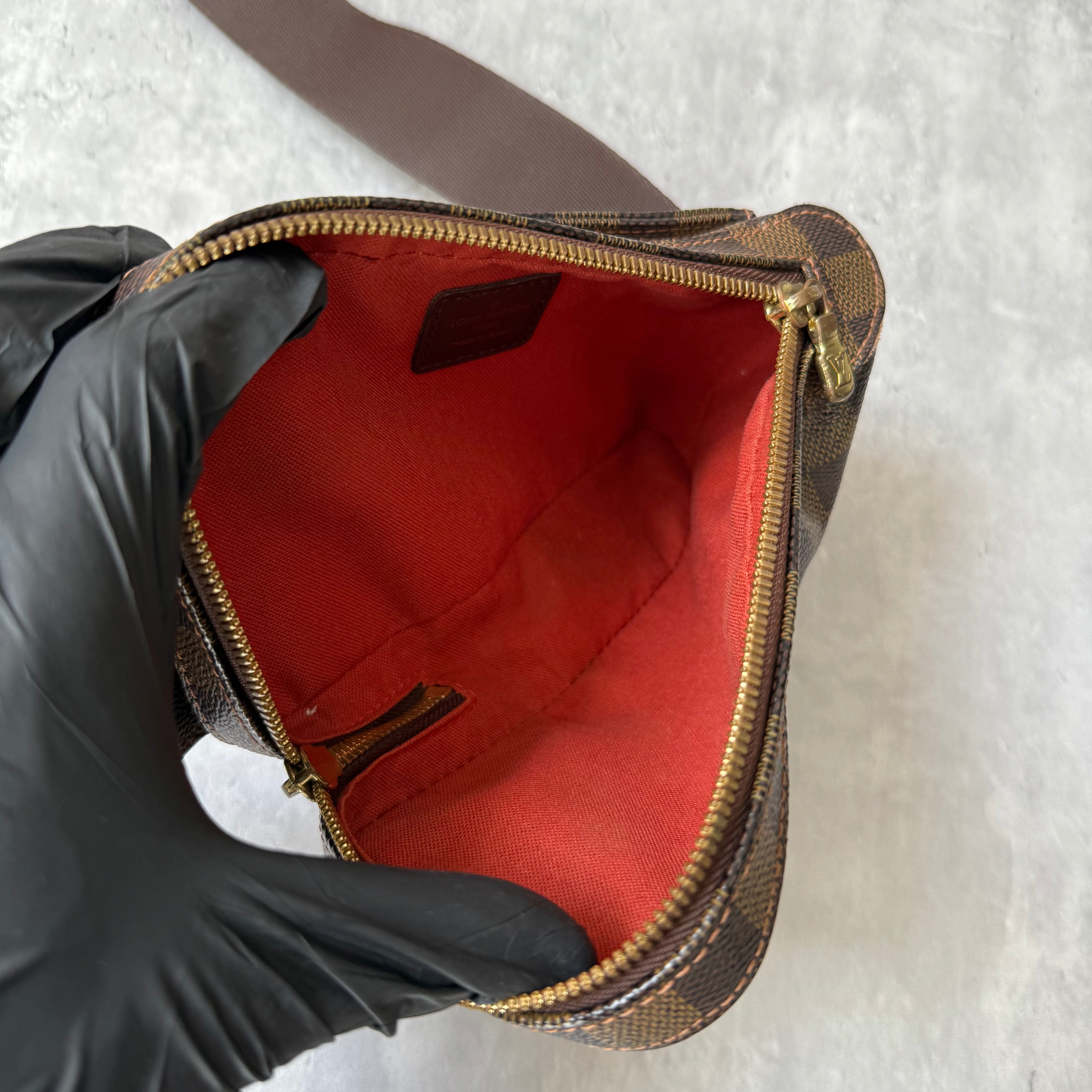 Louis Vuitton Geronimos Bag in brown Damier Ebene canvas with adjustable strap, red interior, and zip closure.