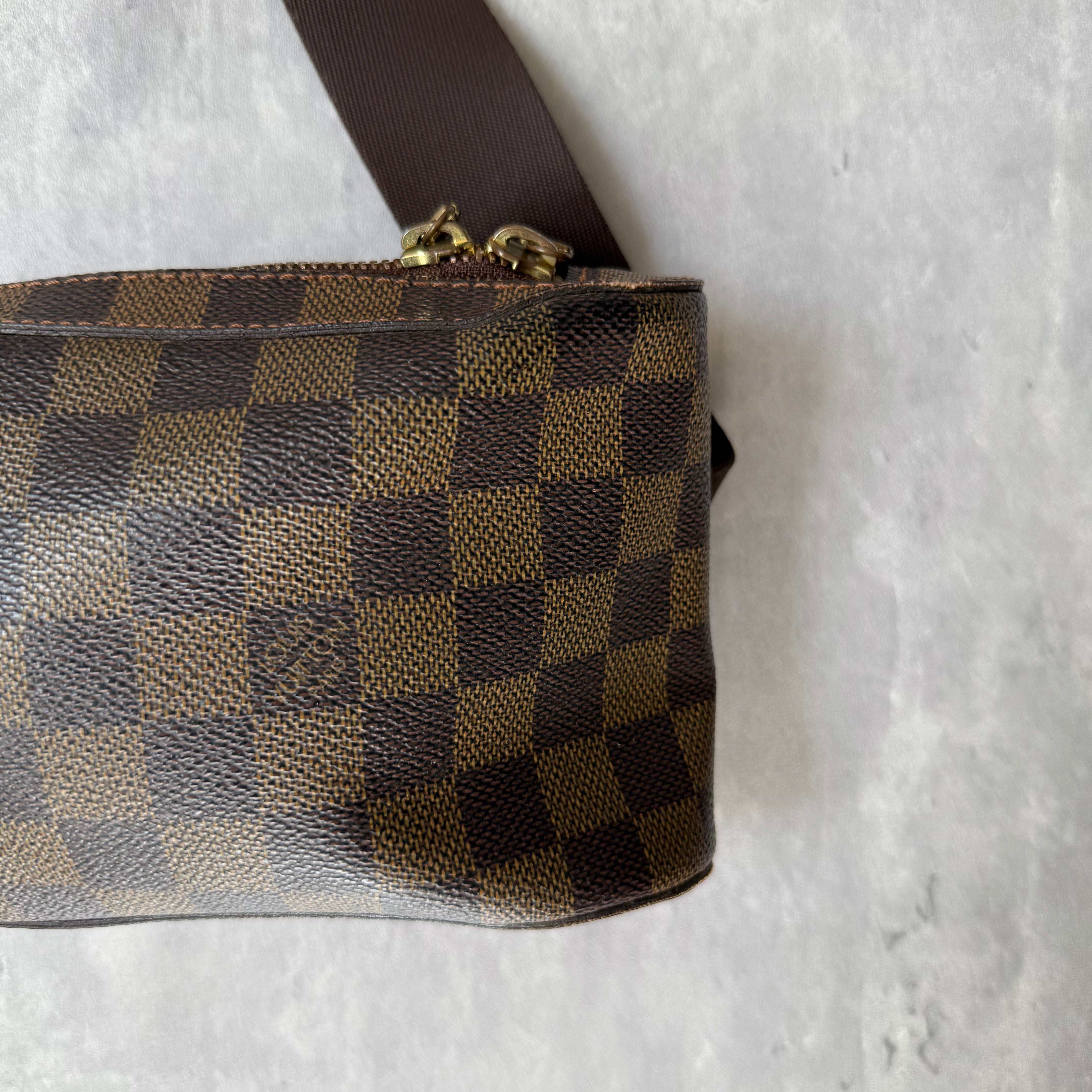 Louis Vuitton Geronimos Bag in brown Damier Ebene canvas with adjustable strap, red interior, and zip closure.