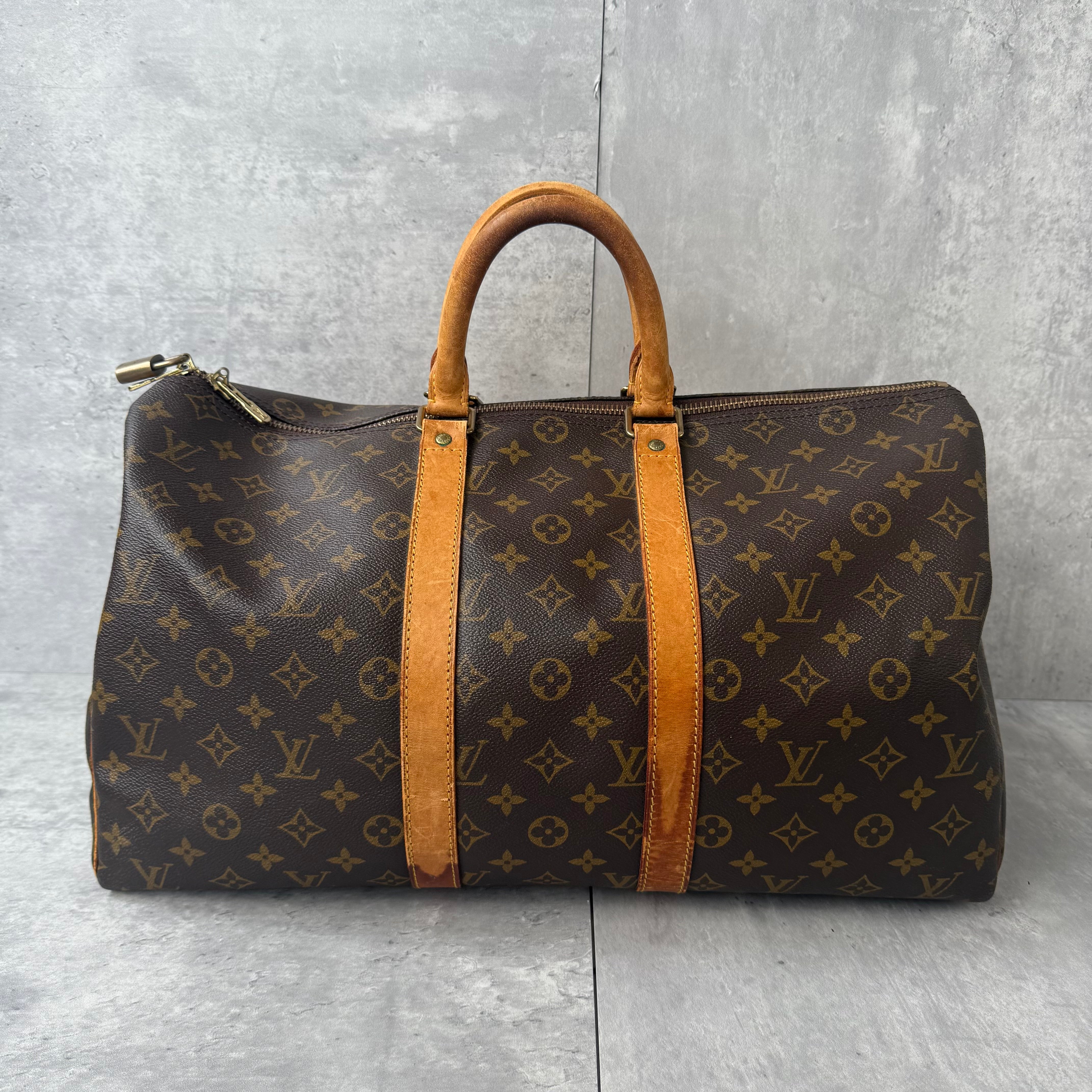 Louis Vuitton Monogram Keepall Duffle Bag in brown coated canvas with natural cowhide leather handles and gold-tone hardware.