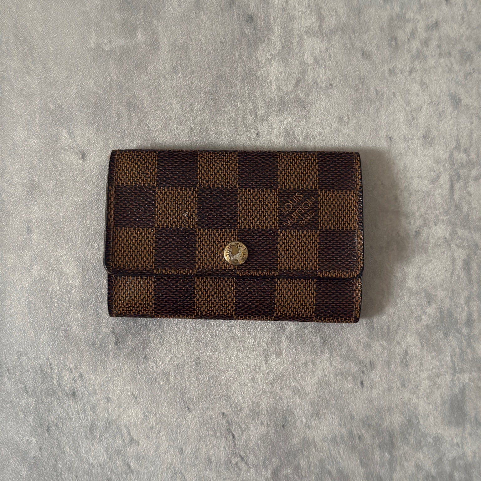 Pre-loved Louis Vuitton Damier Ebene Key Holder with Six Gold-Tone Hooks, Luxury Vintage Designer Accessory with Snap Button Closure.