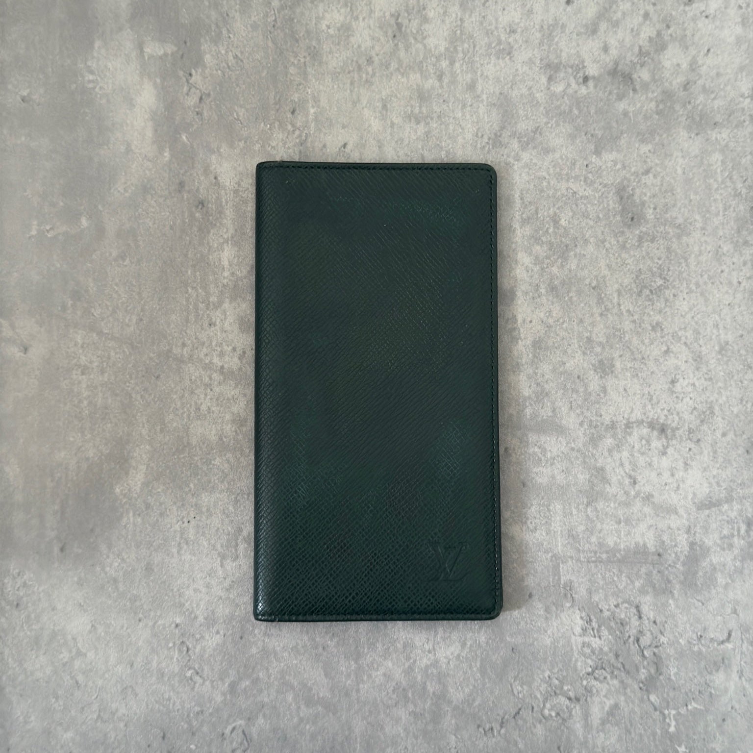 Louis Vuitton Taiga Porte-Valeurs long wallet in green, showcasing the embossed LV logo and a structured interior with multiple card slots and compartments, embodying luxury and organization.