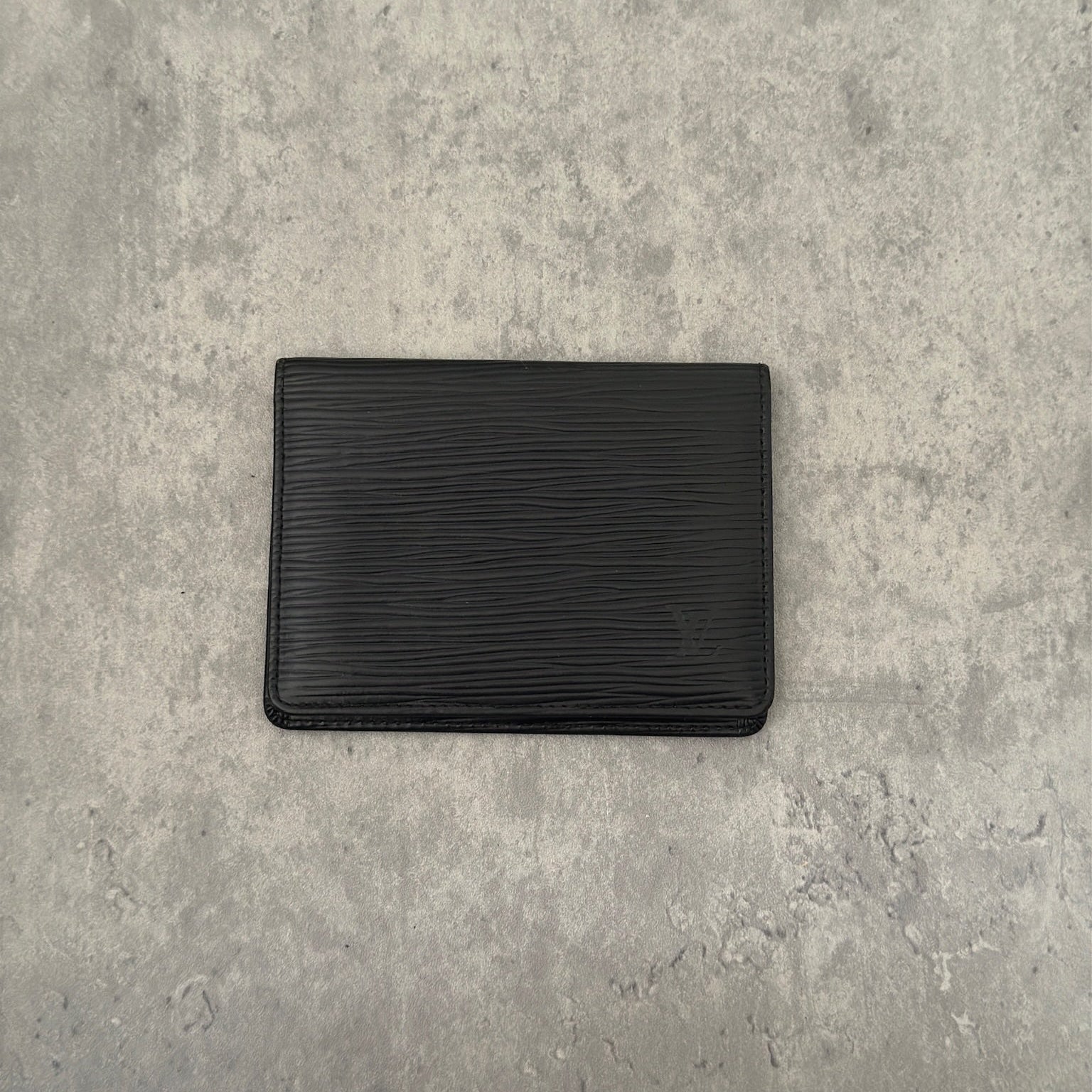 Luxurious black leather Louis Vuitton vintage card, ID, and passport holder featuring embossed logo, designed for sophisticated organization and style.