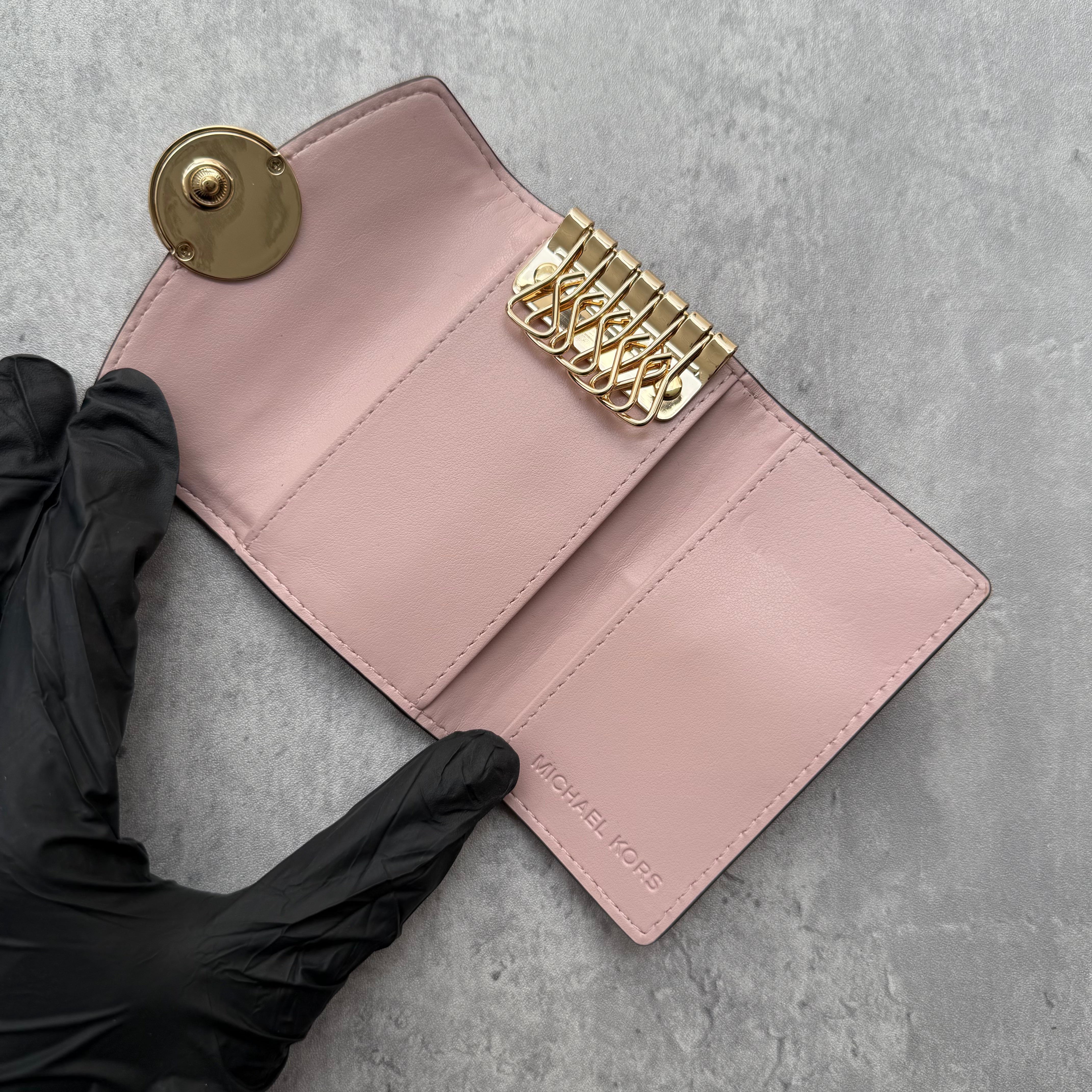 Michael Kors Pink Key Holder in pebbled leather with gold MK logo snap closure and interior key hooks.