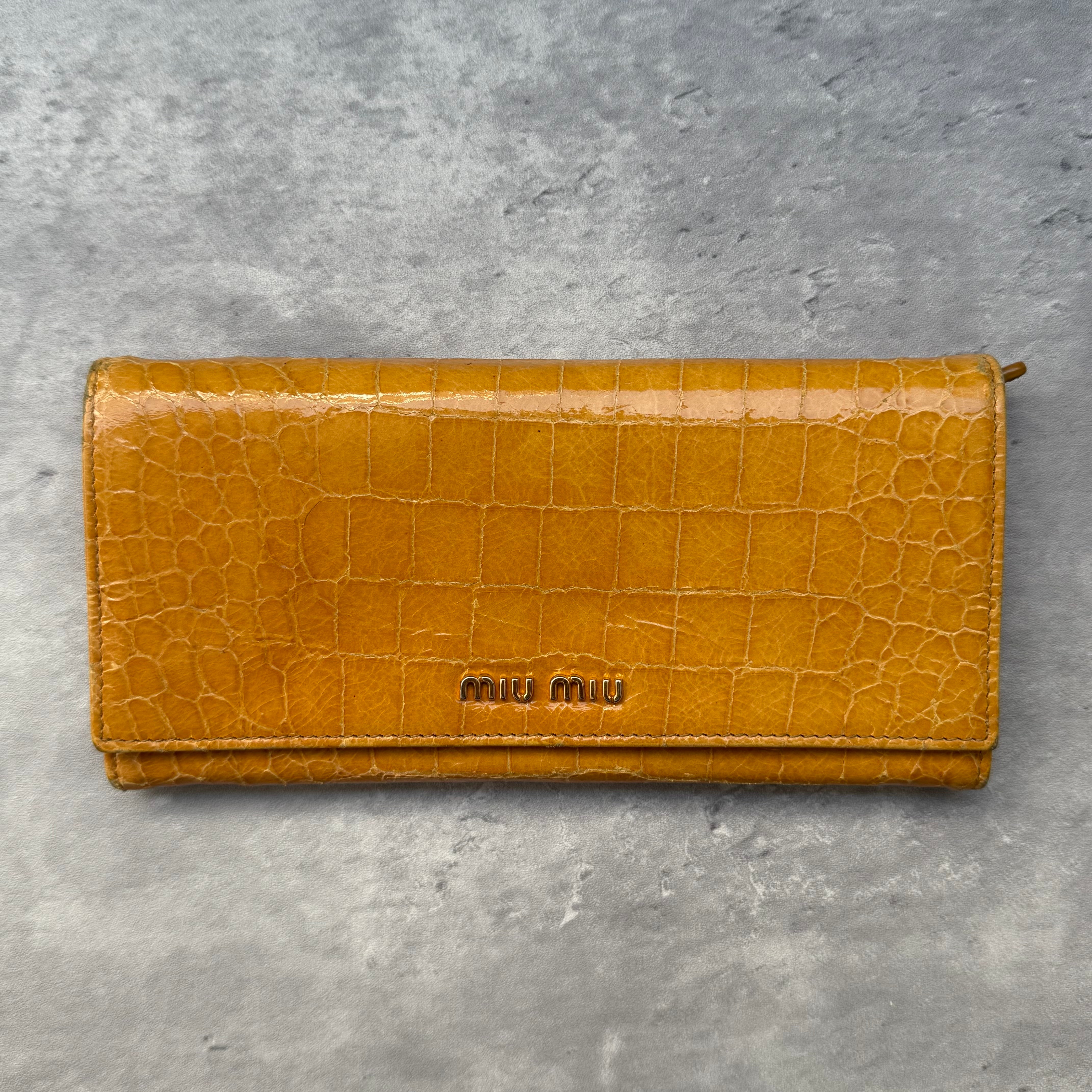 Miu Miu Croc Embossed Long Wallet in deep yellow leather with gold-tone logo, featuring multiple card slots, compartments, and a central zip pocket.