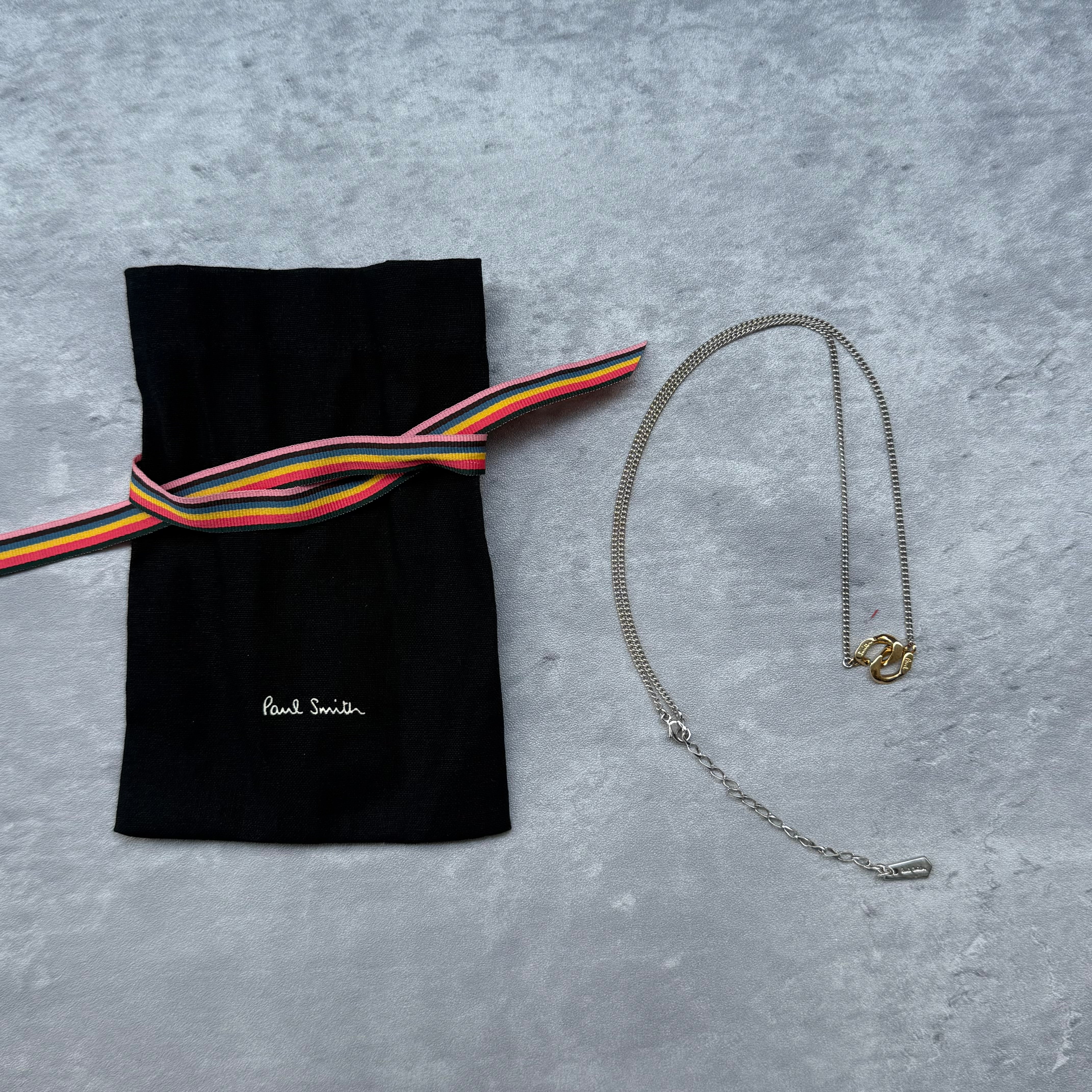 Paul Smith Chain Necklace in silver with gold-tone pendant, includes original pouch with multicolor ribbon tie.