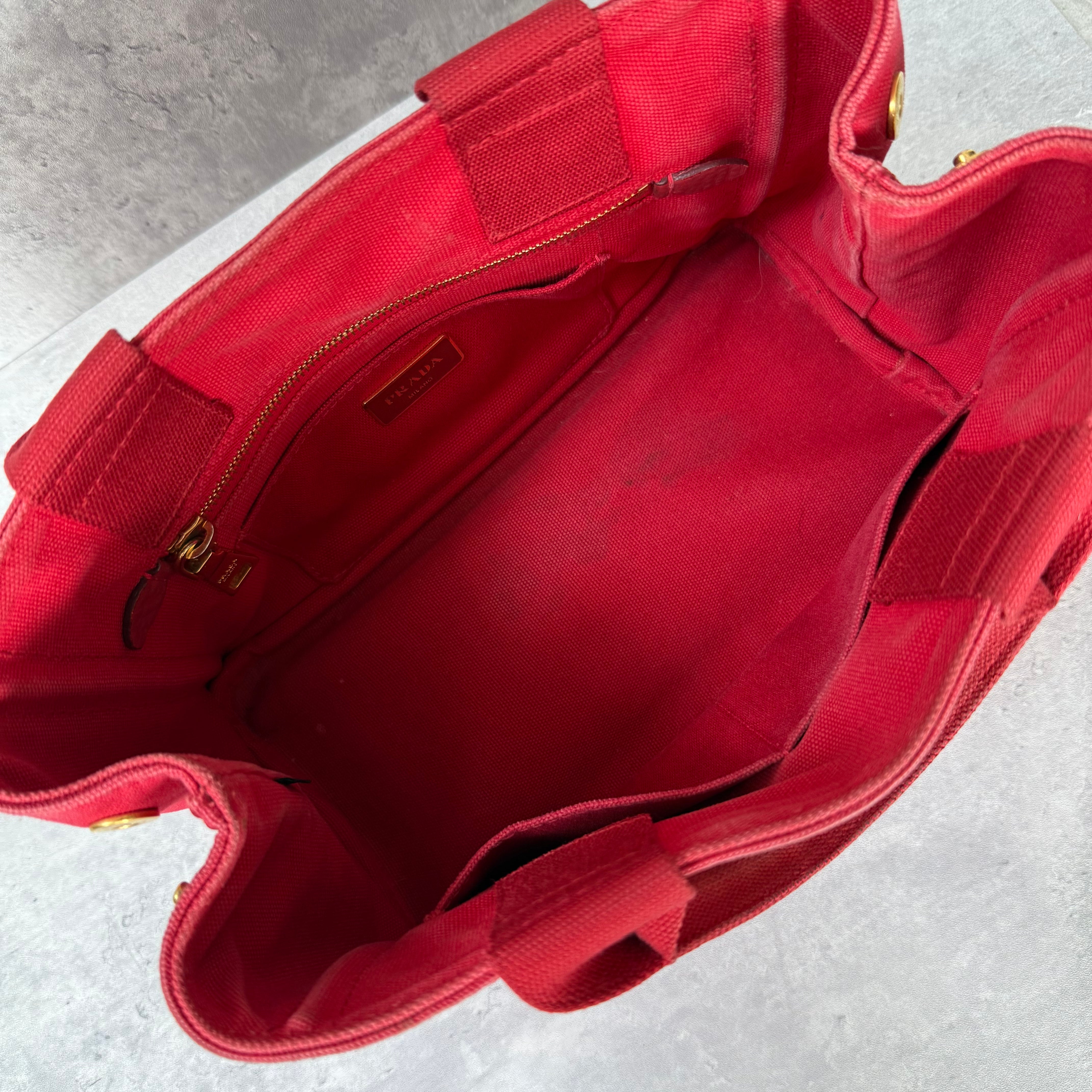 Prada Canapa Tote Bag in red canvas with black logo embroidery, featuring a structured silhouette and dual top handles for effortless style.